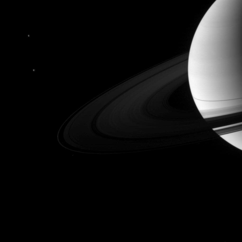 A pair of Saturn's moons, Dione and Tethys, accompany the planet and its rings in this image taken shortly after the planet's August 2009 equinox by NASA's Cassini spacecraft.