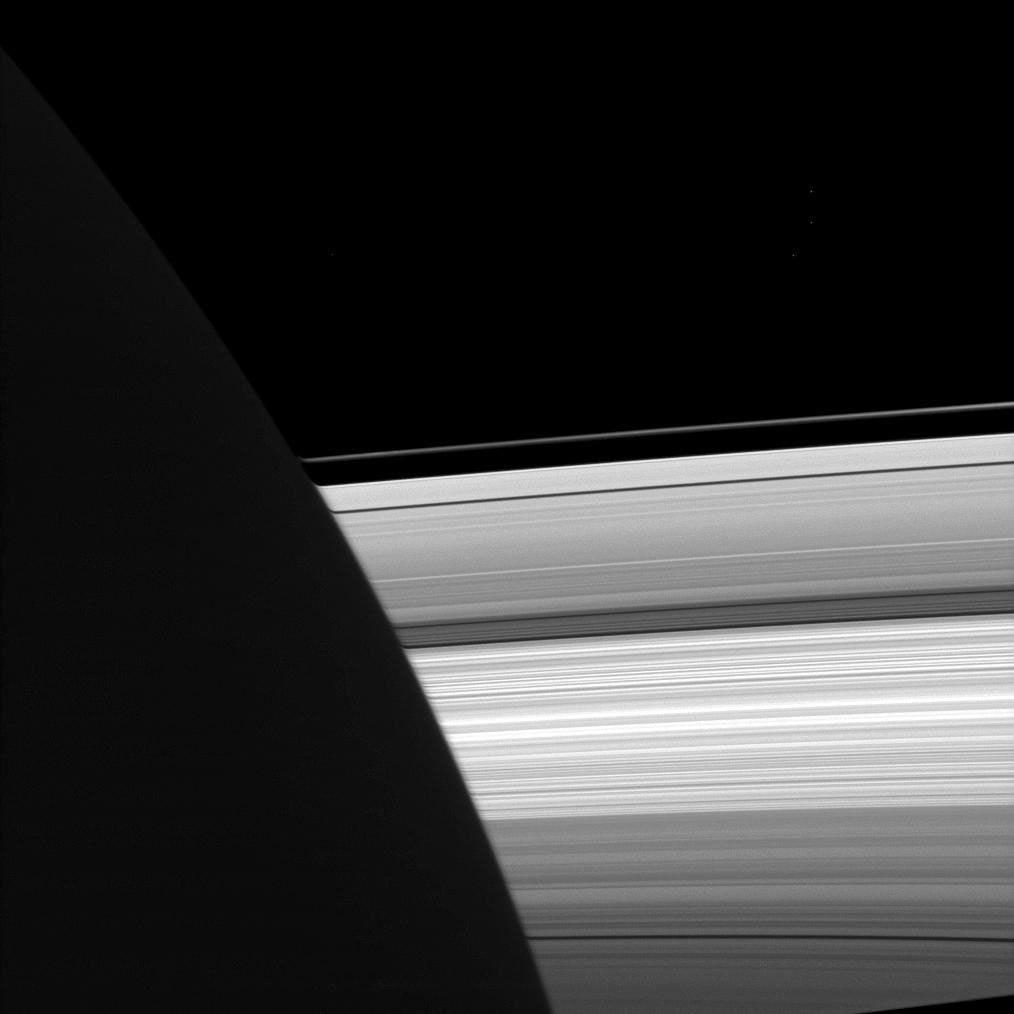 NASA's Cassini spacecraft looks past the night side of Saturn, dimly lit on the left of this image by ringshine, for a subtly distorted view of the planet's rings.