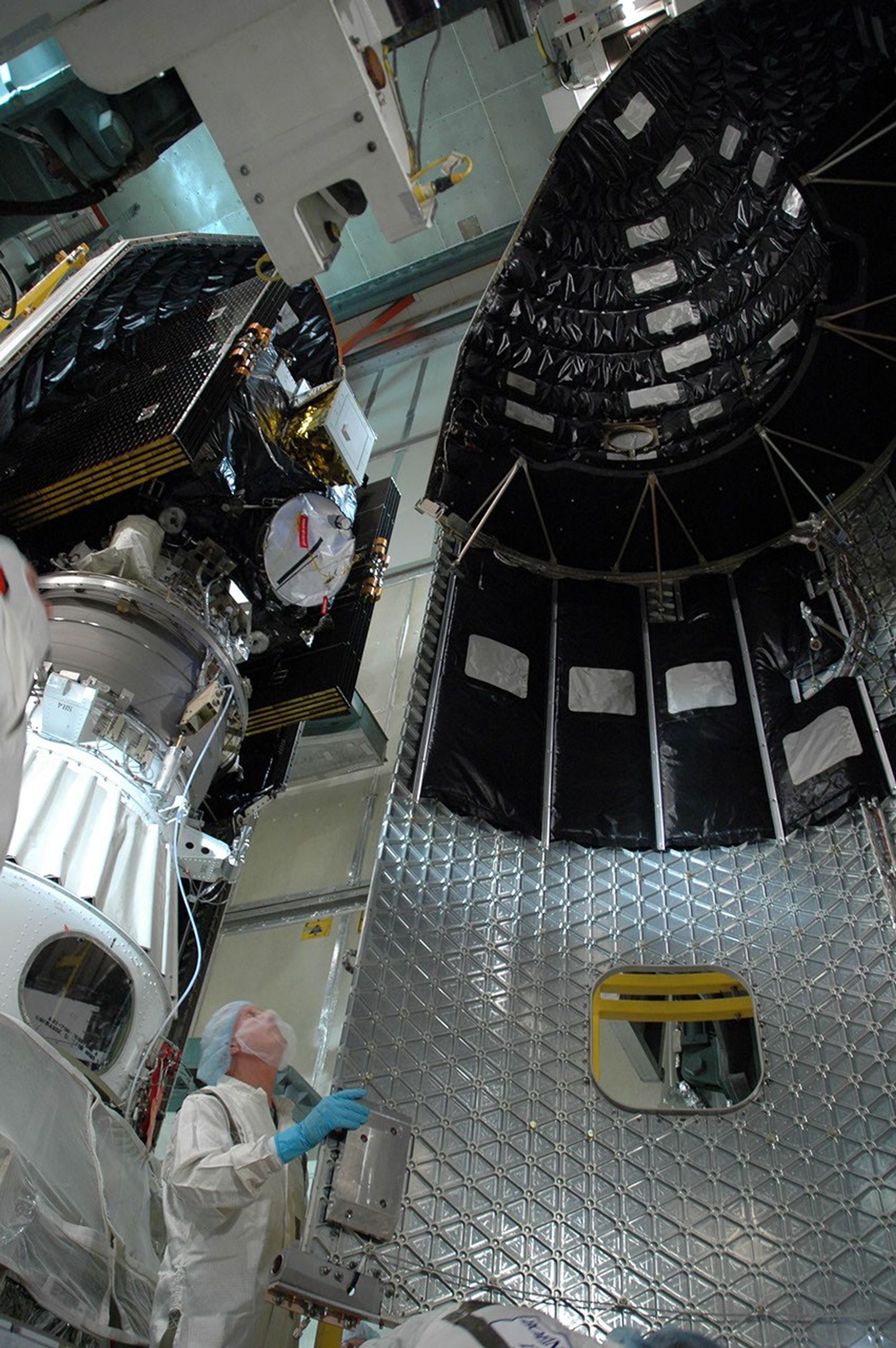 Technician helps guide the second half of the fairing for installation around NASA's Dawn spacecraft.