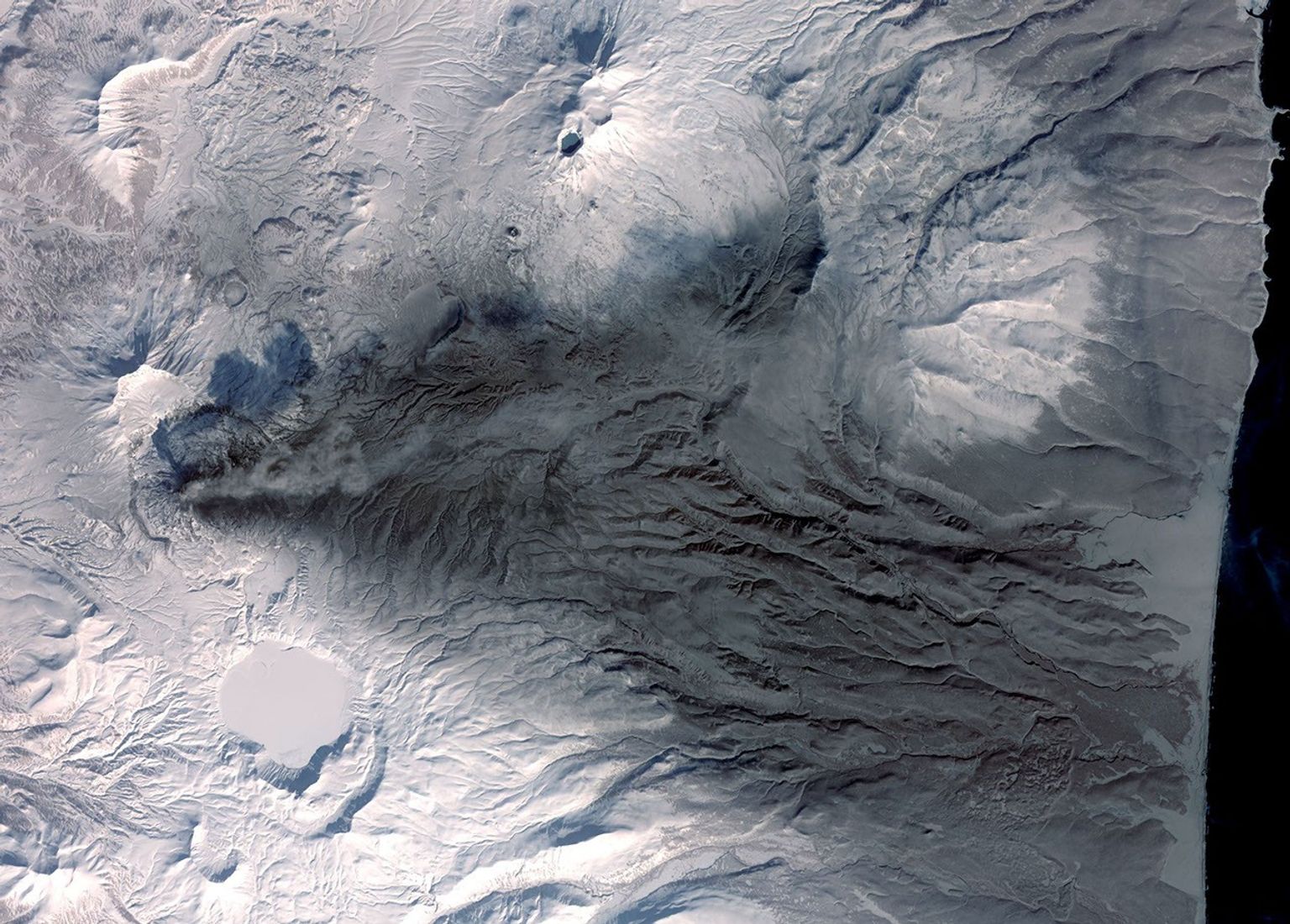 This image acquired by NASA's Terra spacecraft on March 6, 2009, shows early March eruptions of Karymsky volcano on Russia's Kamchatka Peninsula left the usually white snow a gray ashy color.