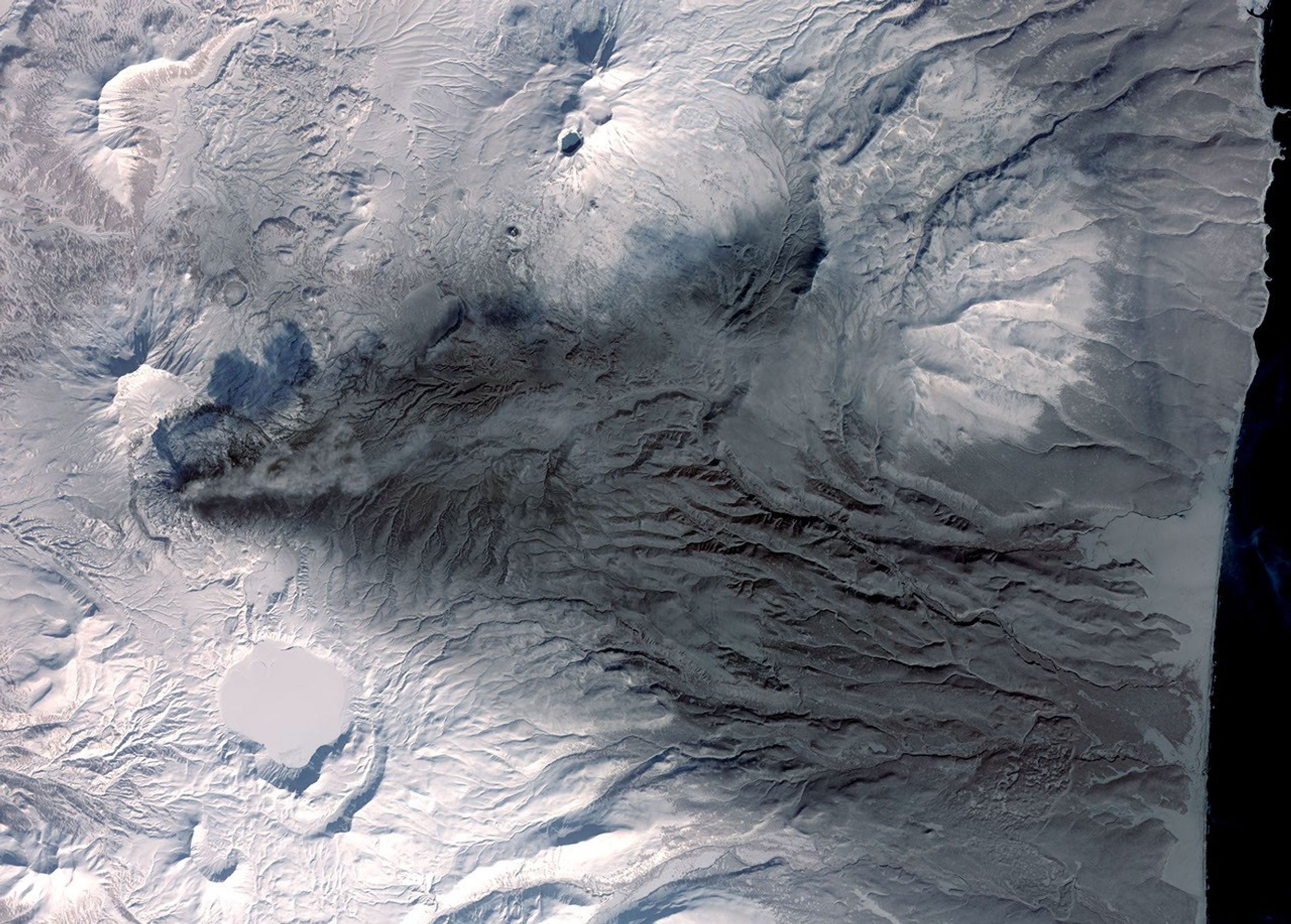 This image acquired by NASA's Terra spacecraft on March 6, 2009, shows early March eruptions of Karymsky volcano on Russia's Kamchatka Peninsula left the usually white snow a gray ashy color.