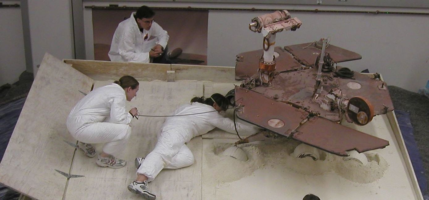 NASA's Mars Exploration Rover team members prepare a testing setup for a subsequent experiment after an experiment driving the rover in a crablike motion, with all four corner wheels angled to the right.
