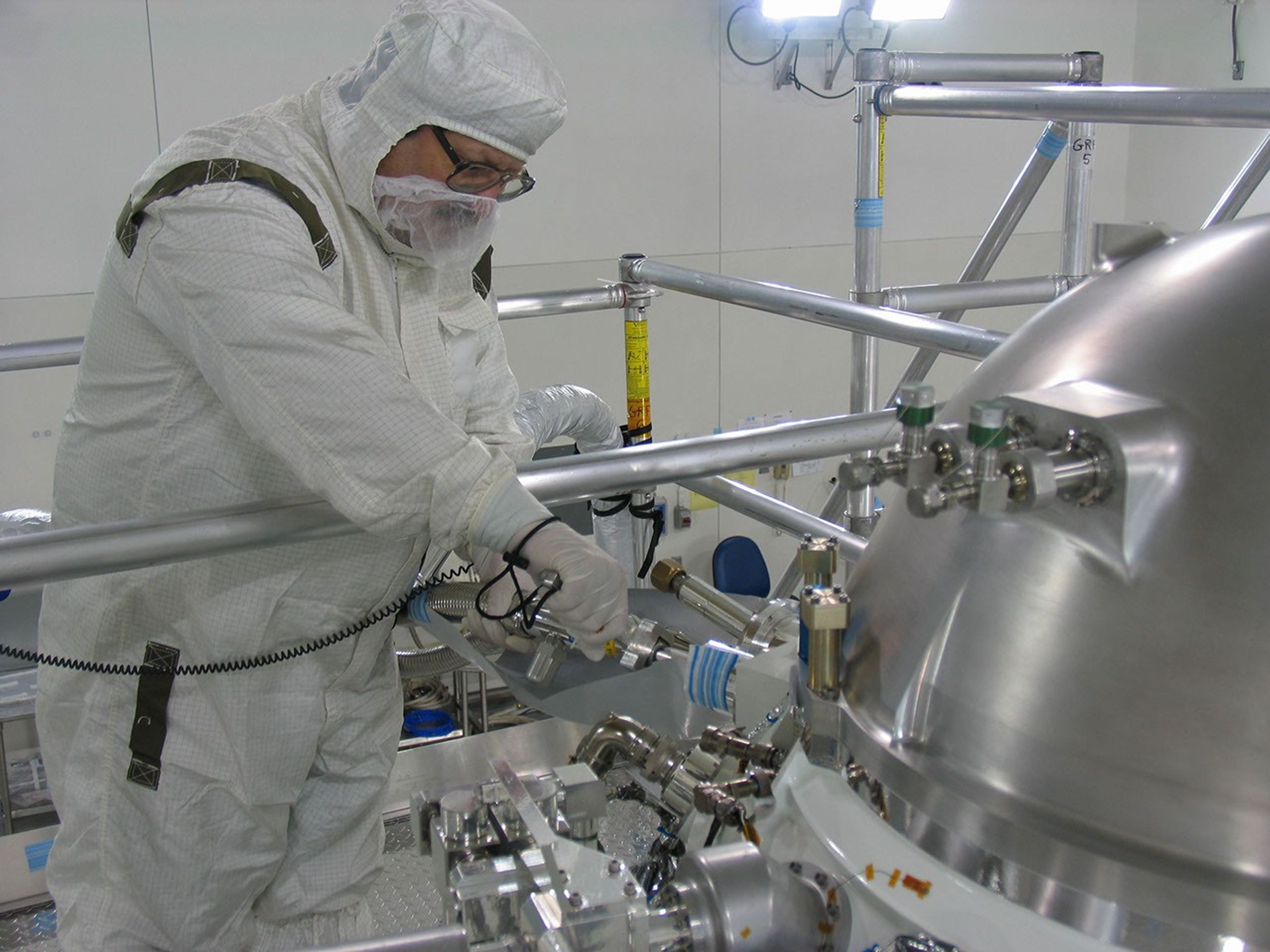 An engineer loads hydrogen gas into the Wide-Field Infrared Survey Explorer in a clean room at the Vandenberg Air Force Base, Calif. The hydrogen is cooled and frozen inside a Thermos-like bottle, called the cryostat, which keeps the science instrument