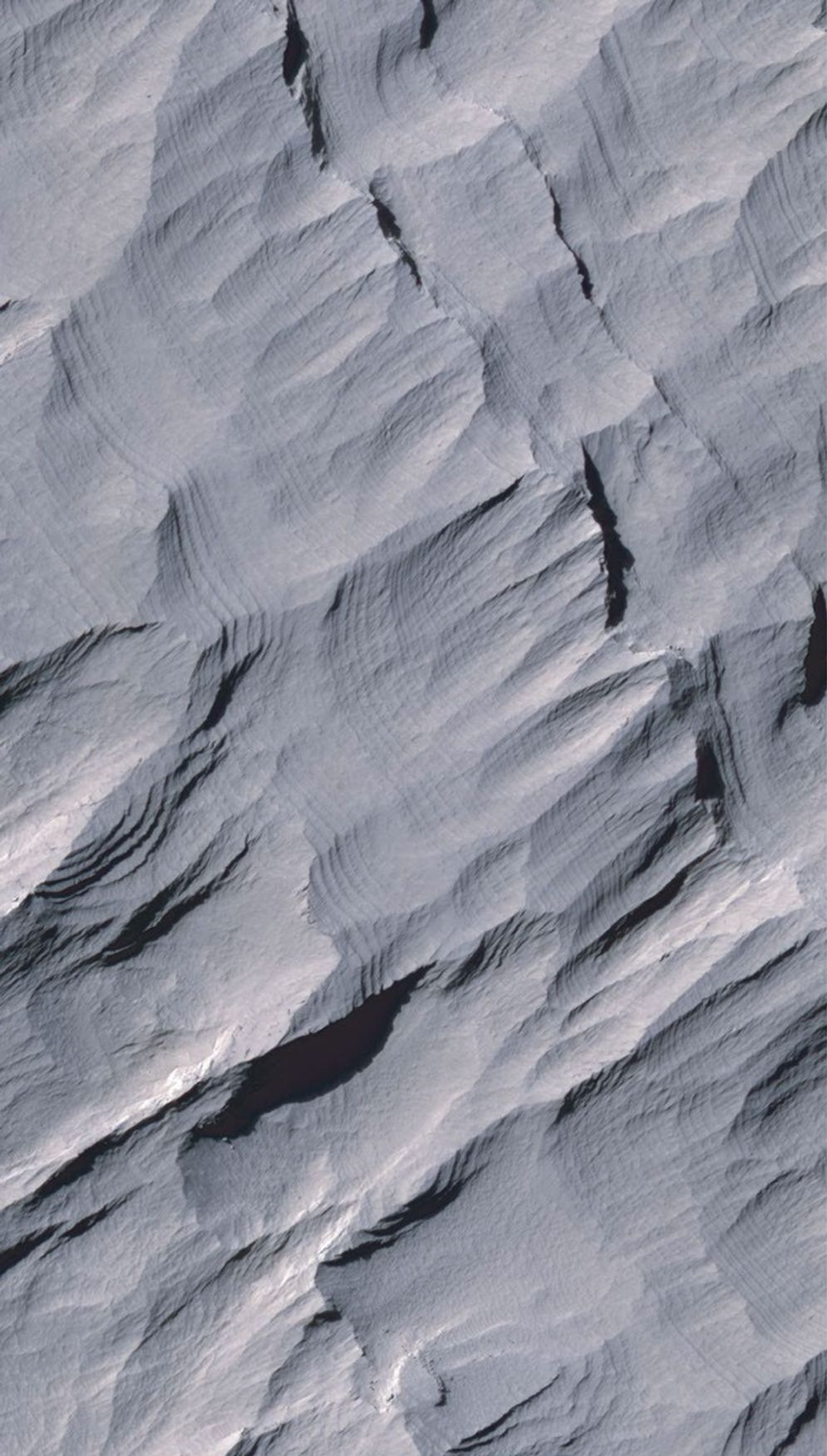 Layers of rock in the upper portion of a tall mound near the center of Gale Crater on Mars exhibit a regular thickness of several meters in this image taken by NASA's Mars Reconnaissance Orbiter.