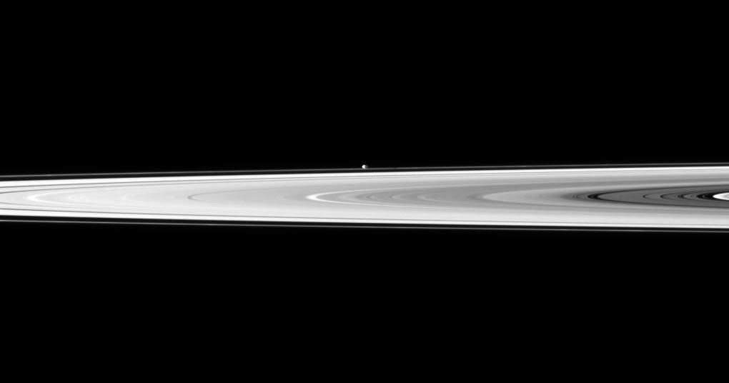 The tiny moon Pandora appears beyond the bright disk of Saturn's rings in this image taken by NASA's Cassini spacecraft. Pandora orbits outside the F ring and, in this image, is farther from Cassini than the rings are.