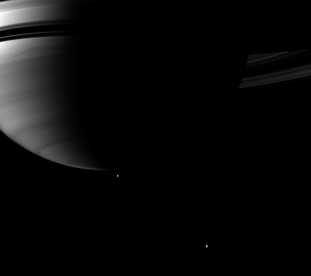 Looking up toward Saturn's southern hemisphere, NASA's Cassini spacecraft pictures a pair of the planet's moons orbiting in the distance. Tethys and Rhea orbit in the plane of the planet's rings, but appear to be below the planet in this view.