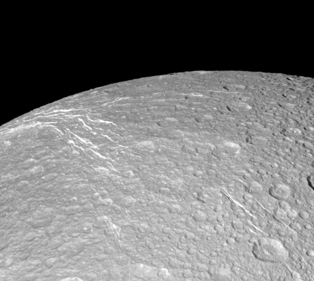 NASA's Cassini spacecraft looks across the surface of Saturn's moon Dione and details the 'wispy' terrain first chronicled by Voyager. This fractured terrain covers the trailing hemisphere of Dione.