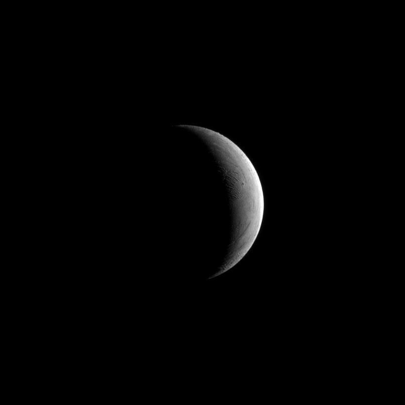 NASA's Cassini spacecraft captures a crescent of Saturn's moon Enceladus. Lit terrain seen here is in the area between the leading hemisphere and Saturn-facing side of Enceladus (504 kilometers, or 313 miles across). North on Enceladus is up.