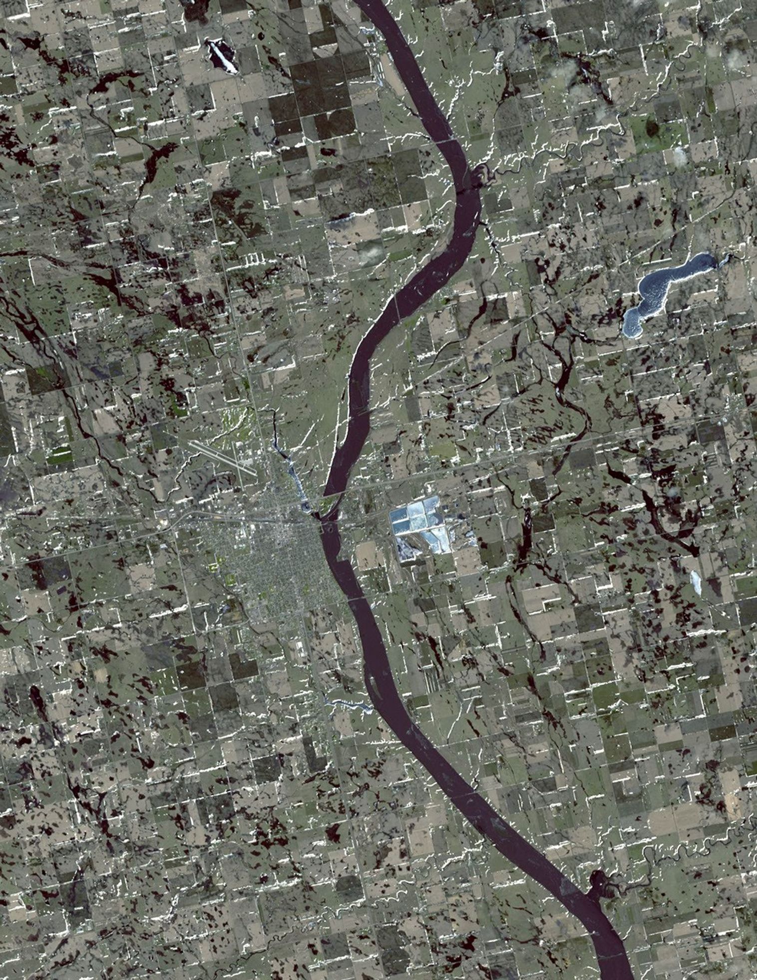 In this simulated natural color image of Huron, South Dakota, captured by NASA's Terra spacecraft on March 20, 2010, frozen lakes and ponds appear blue, bare fields are tan, and fields with minor vegetation are gray-green.