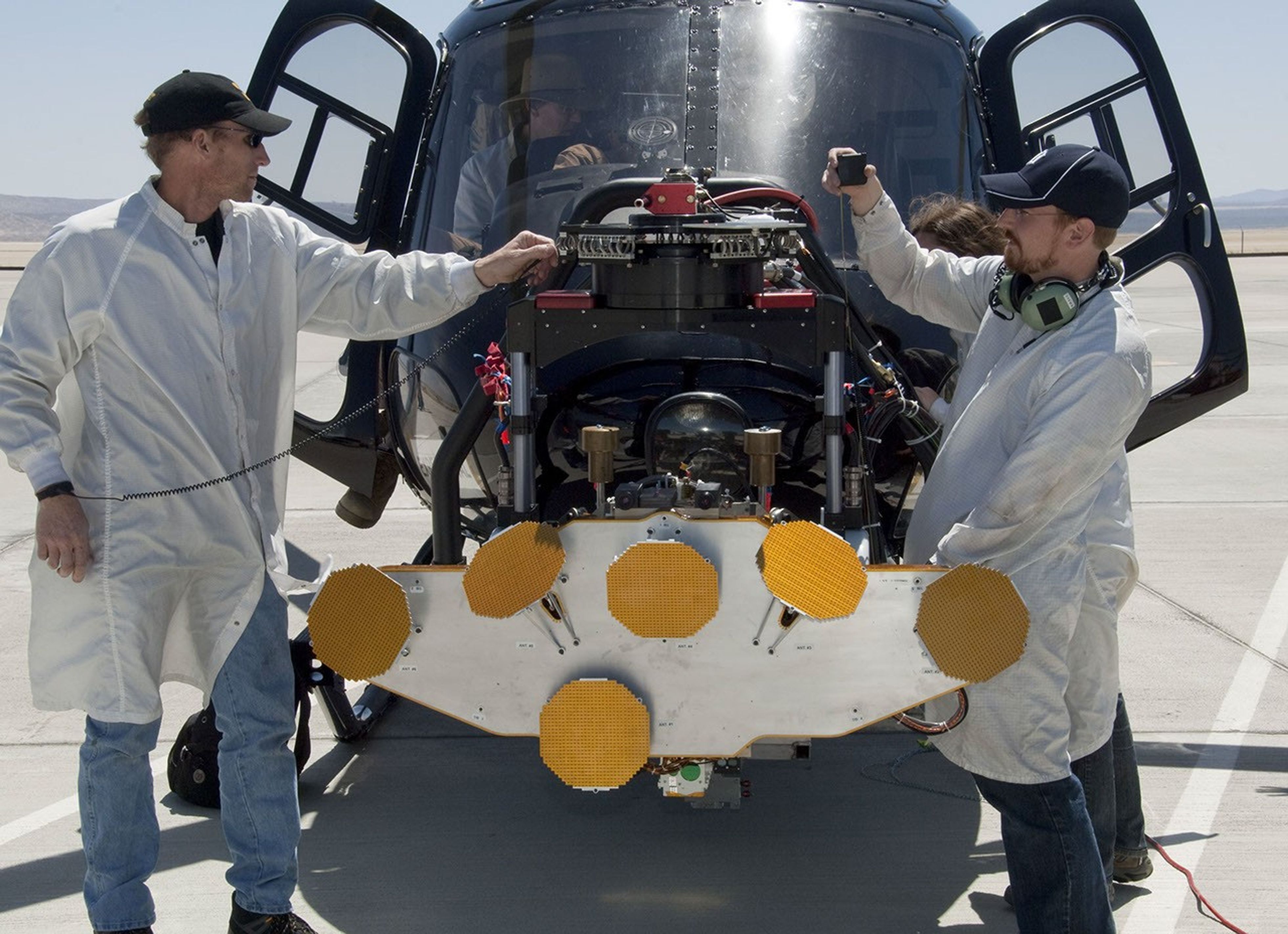 In advance of a testing flight at NASA Dryden Flight Research Center, members of the test team prepare the engineering model of the Mars Science Laboratory descent radar on the nose gimbal of a helicopter. The yellow disks are the radar's antennae.