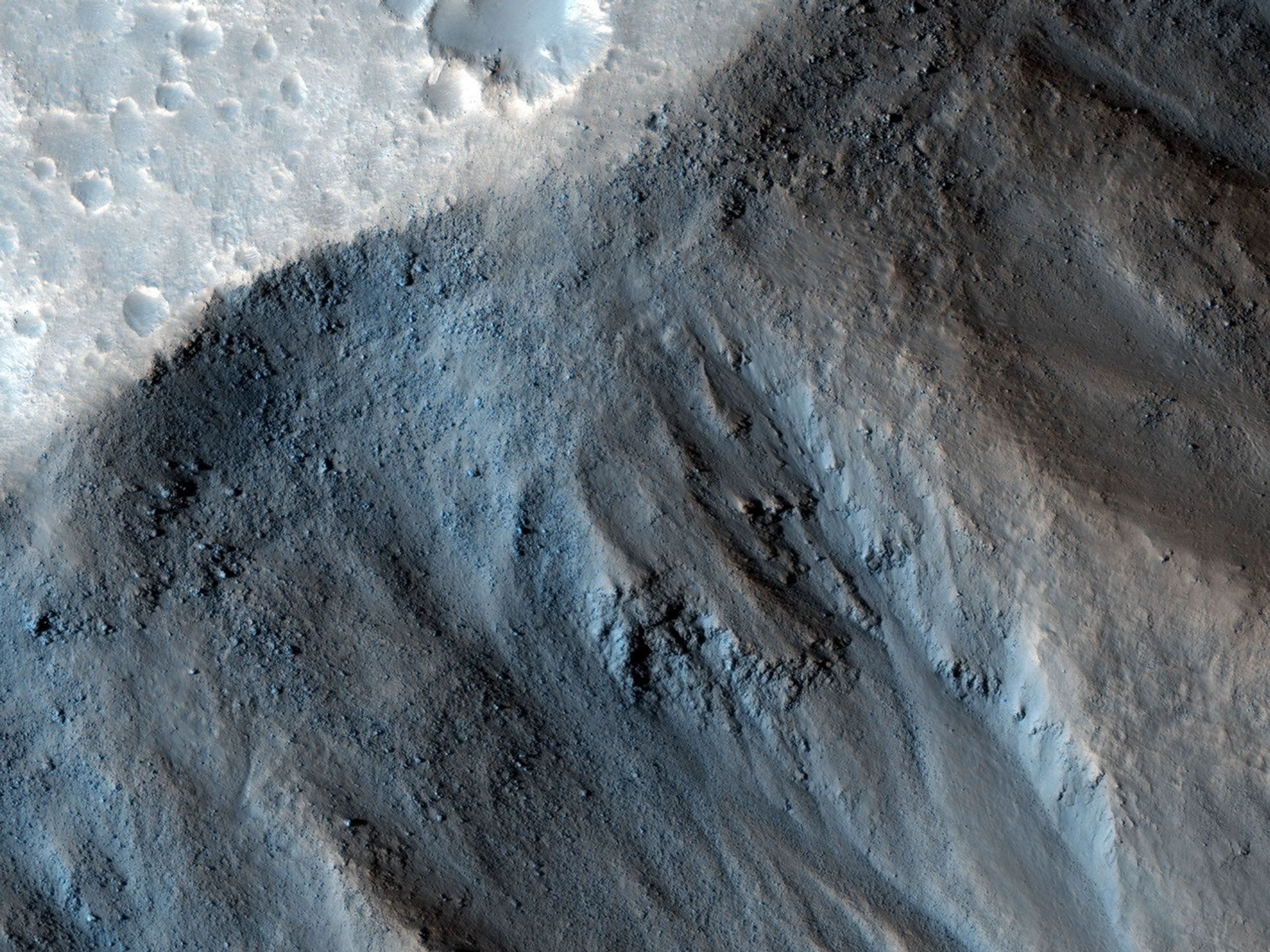 This observation from NASA's Mars Reconnaissance Orbiter shows the very steep side of a plateau, part of the northern limit of the Kasei Valles system, which is one of the largest outflow channel systems on Mars.