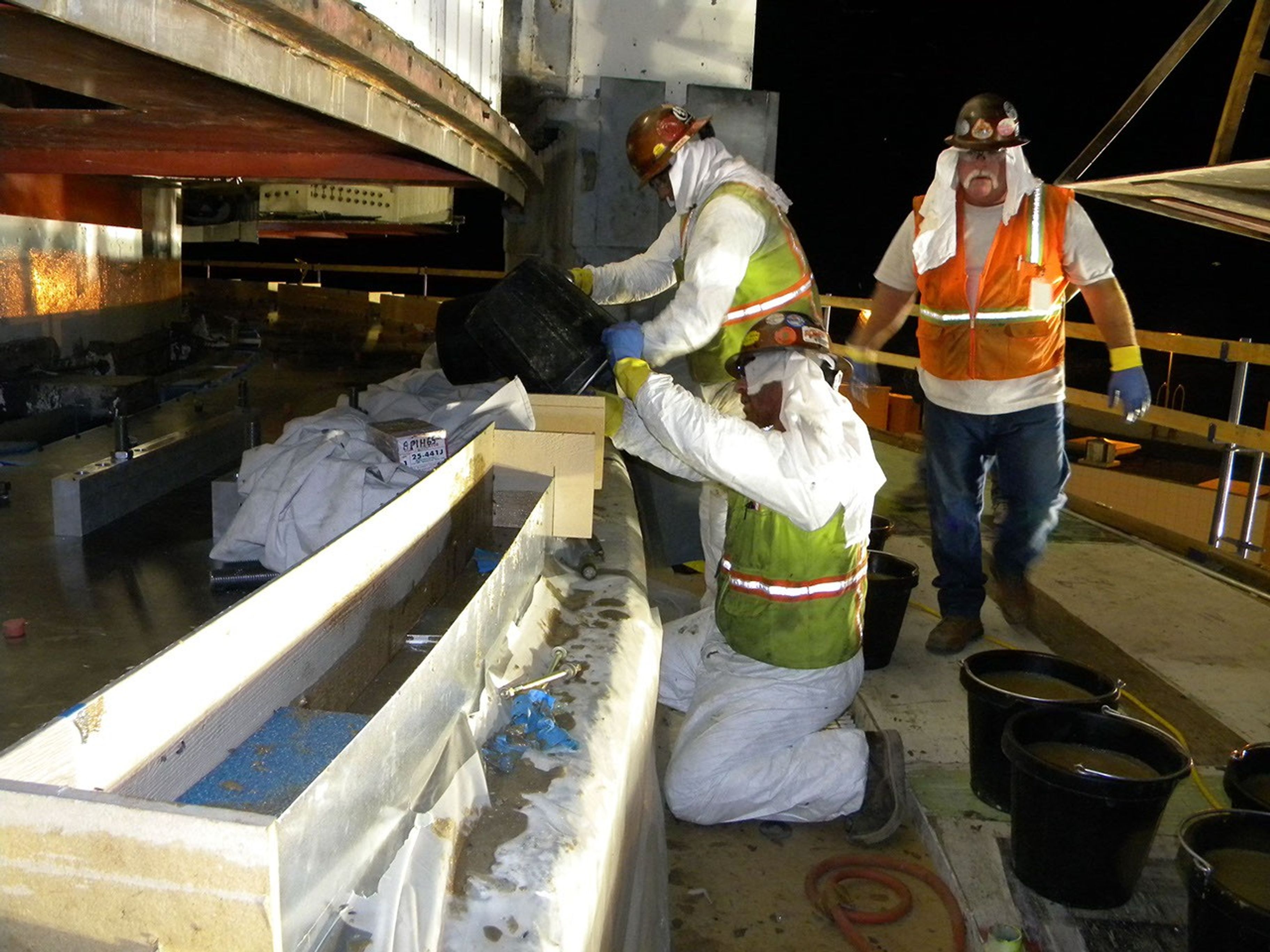 Workers at NASA's Deep Space Network complex in Goldstone, Calif., pour in a new epoxy grout as the giant 'Mars antenna' undergoes major surgery. The grout is part of the hydrostatic bearing assembly, which enables the antenna to rotate horizontally.