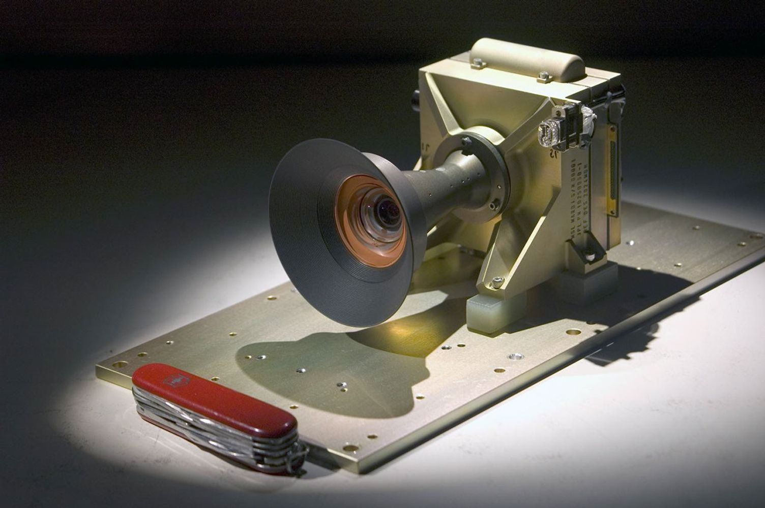 A pocketknife provides scale for this image of the Mars Descent Imager camera; the camera will fly on the Curiosity rover of NASA's Mars Science Laboratory mission. Malin Space Science Systems, San Diego, Calif., supplied the camera for the mission.