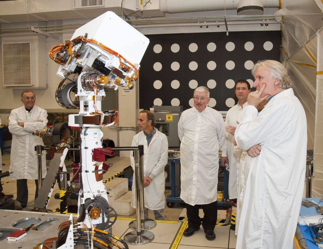 A group of members from the Jet Propulsion Laboratory watch the motions of an engineering model of the camera mast for NASA's Mars rover Curiosity on March 5, 2010.