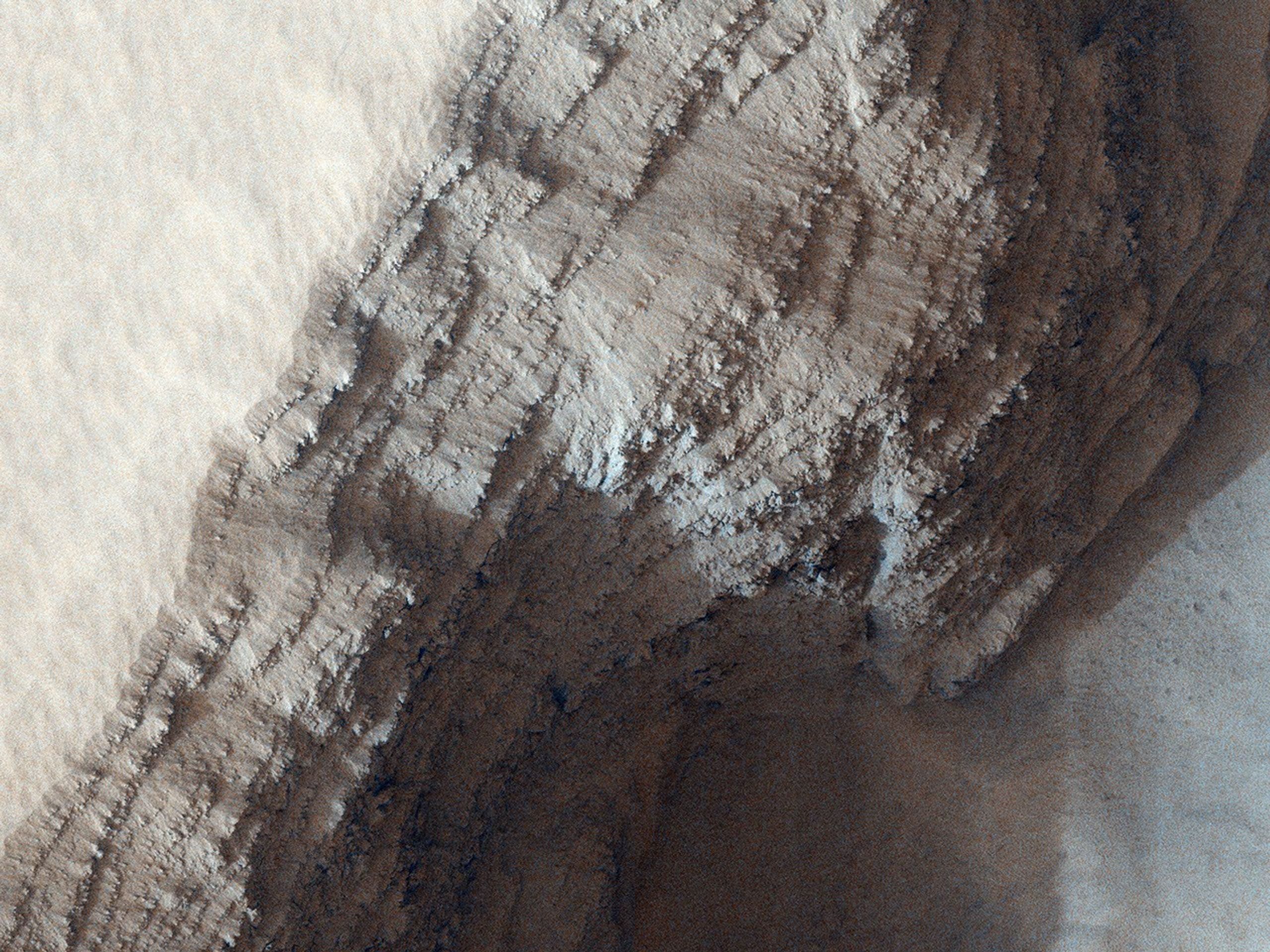 This observance from NASA's Mars Reconnaissance Orbiter covers a pit in the lower West flank of Arsia Mons, one of the four giant volcanos of the Tharsis region. Many layers are exposed in the pit, probably marking individual lava flows.