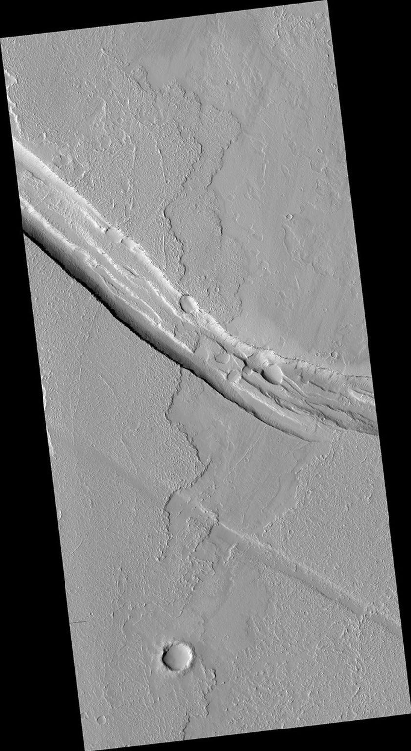 This image from NASA's Mars Reconnaissance Orbiter shows a graben (a trough formed when the ground drops between two parallel faults) and a lava flow in the Tharsis volcanic province of Mars. North is up.