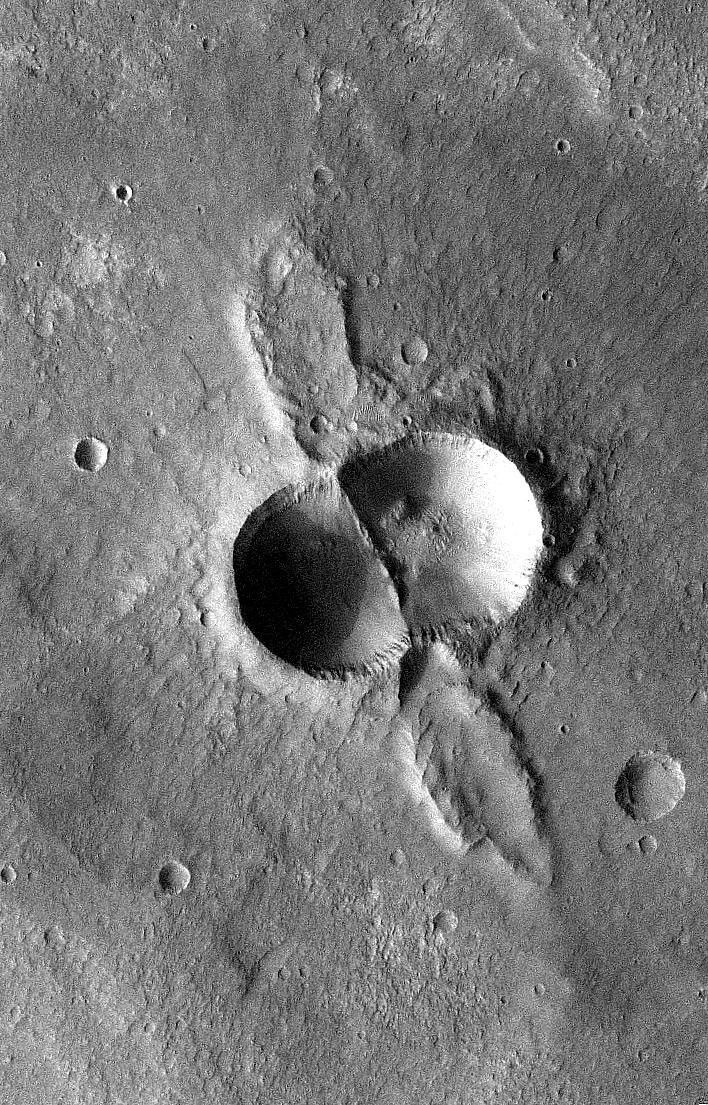 If a meteorite breaks in two shortly before hitting the ground, the typical bowl shape of a single impact crater becomes doubled. This image is from NASA's Mars Odyssey, one of an 'All Star' set.