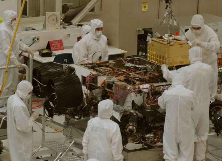 In this photograph, technicians and engineers inside a clean room at NASA's Jet Propulsion Laboratory, Pasadena, Calif., position NASA's Sample Analysis at Mars (SAM) above the mission's Mars rover, Curiosity, for installing the instrument.