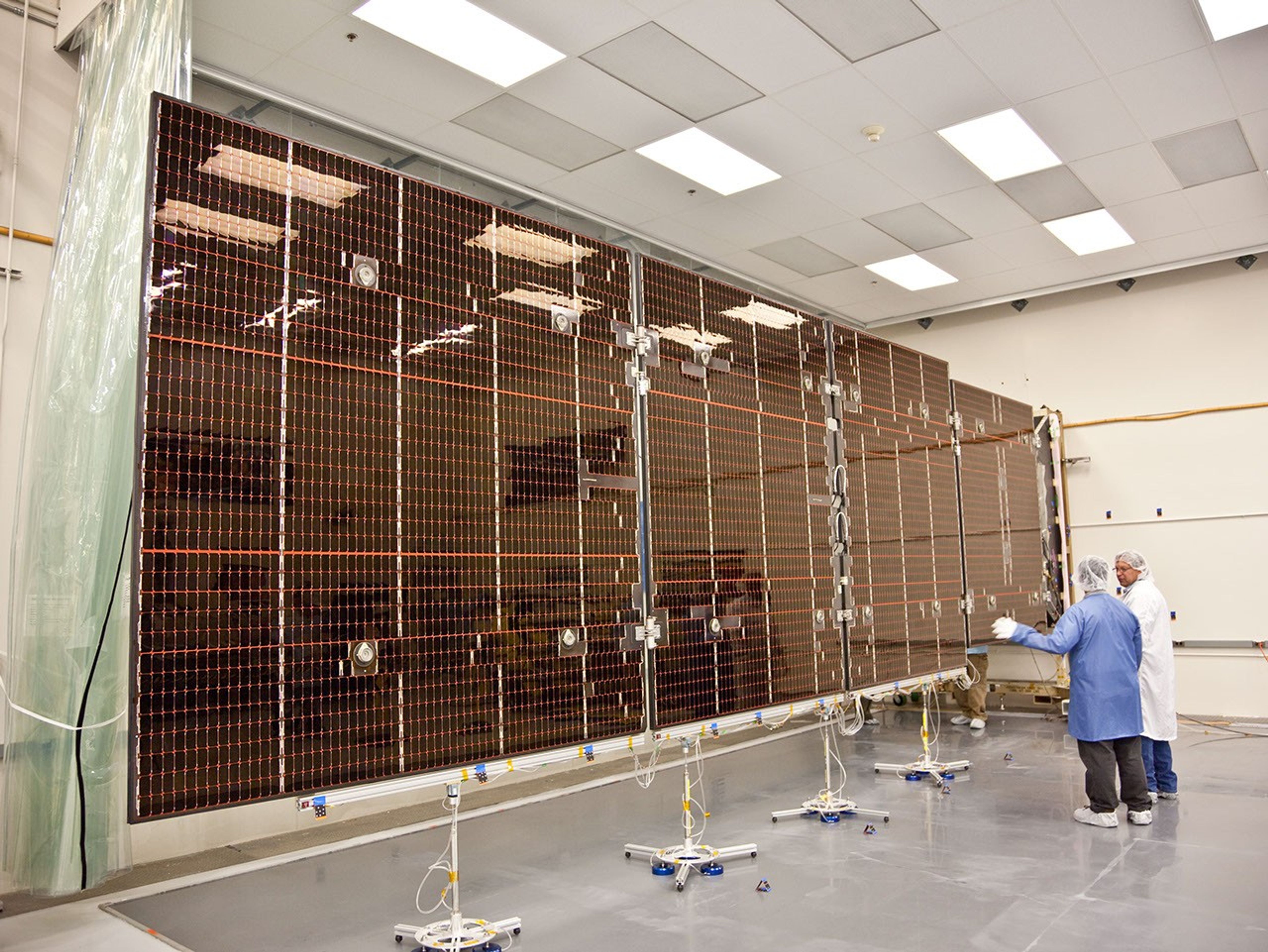 Technicians test the deployment of one of the three massive solar arrays that power NASA's Juno spacecraft.