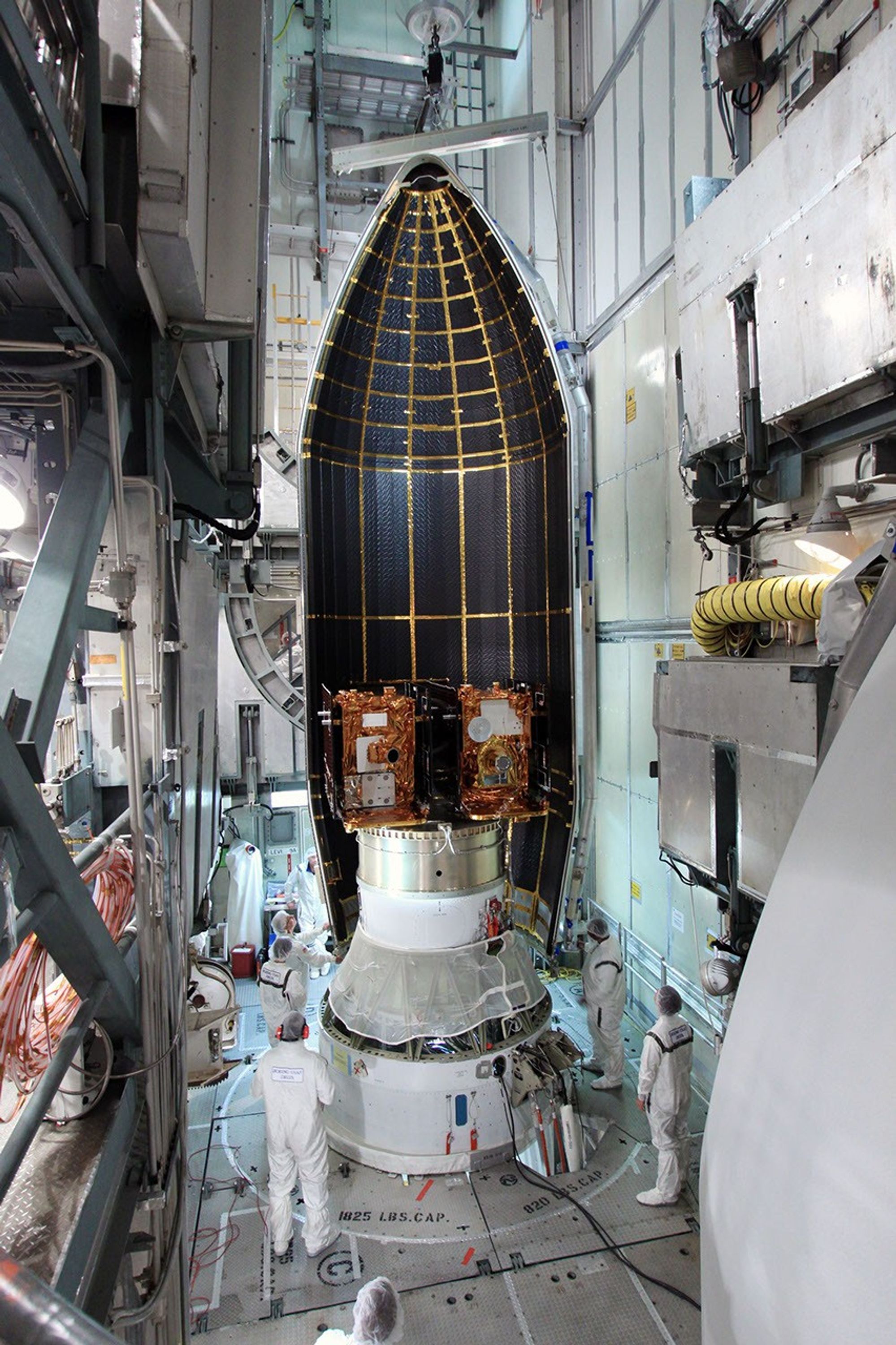 Spacecraft technicians monitor the movement of a section of the clamshell-shaped Delta payload fairing as it encloses NASA's twin Gravity Recovery and Interior Laboratory spacecraft at Cape Canaveral Air Force Station in Florida on Aug. 23, 2011.