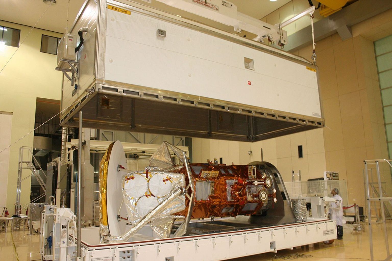 Technicians lower the cover over the shipping container holding the international Aquarius/SAC-D spacecraft at Brazil's National Institute for Space Research.