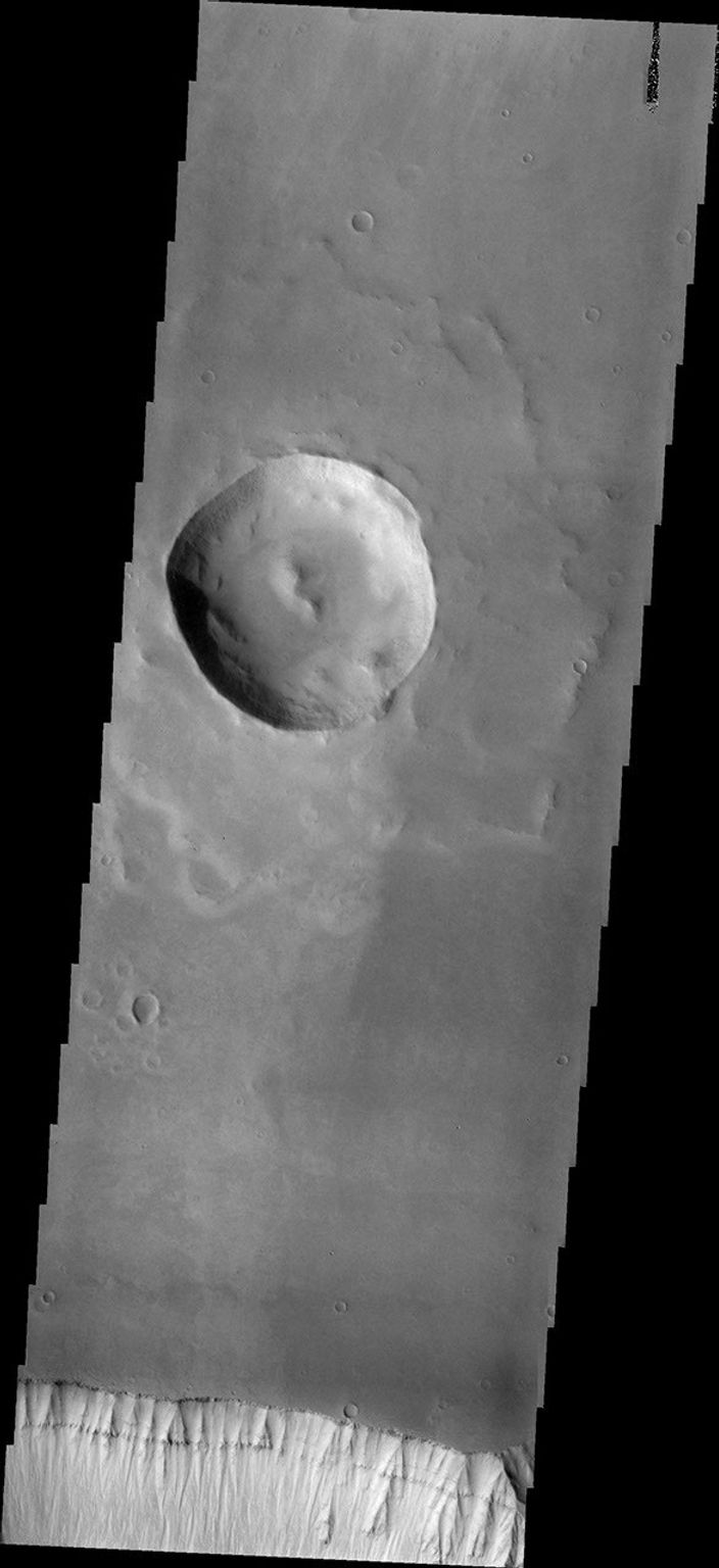 At the bottom of this image from NASA's Mars Odyssey is the cliff-face that is the sidewall of Ophir Chasma. Layering is easily visible in the upper cliff wall, with the thickness of the surface clearly visible.