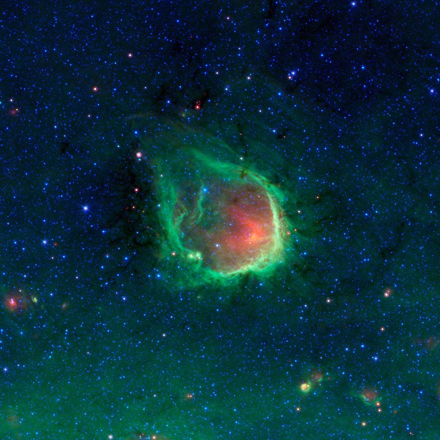 This glowing emerald nebula seen by NASA's Spitzer Space Telescope is named RCW 120; this region of hot gas and glowing dust can be found in the murky clouds encircled by the tail of the constellation Scorpius.