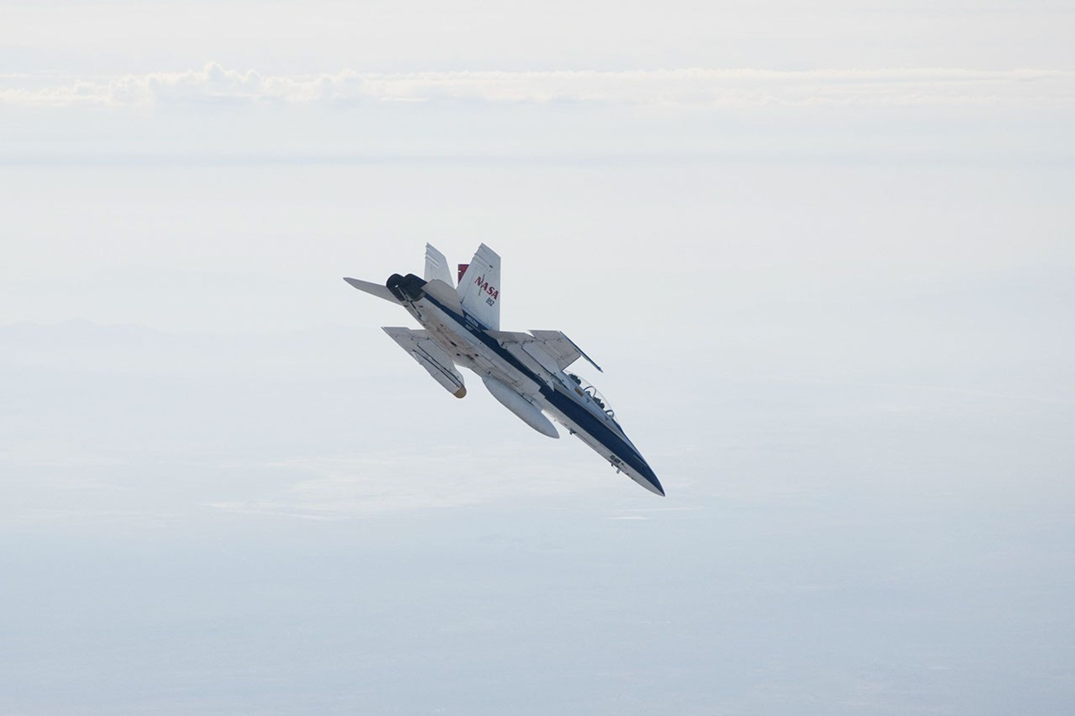 A NASA Dryden Flight Research Center F/A-18 852 aircraft makes a 40-degree dive during June 2011 flight tests of a Mars landing radar. A test model of the landing radar for NASA's Mars Science Laboratory mission is inside a pod under the left wing.