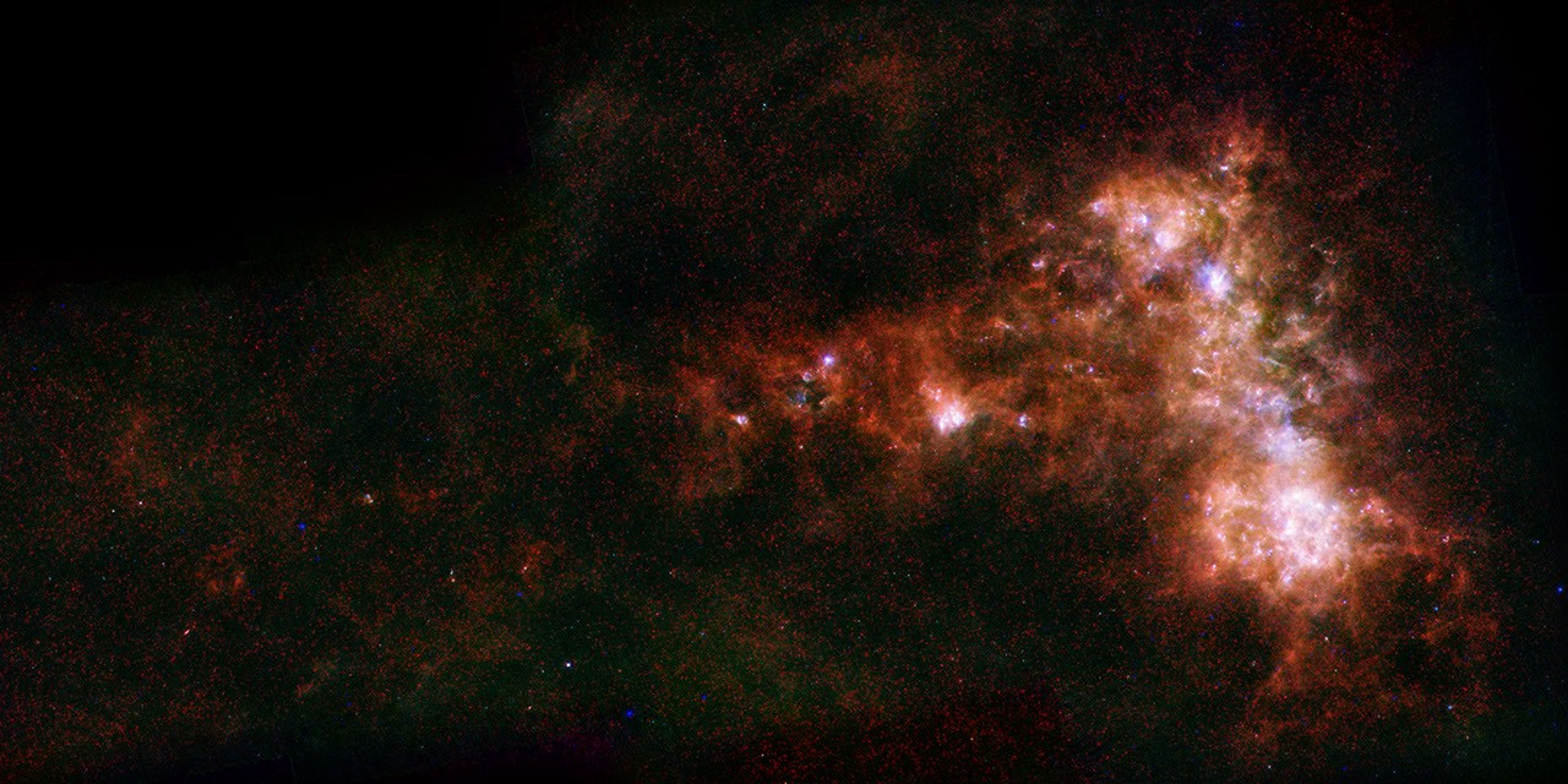In combined data from ESA's Herschel and NASA's Spitzer telescopes, irregular distribution of dust in the Small Magellanic Cloud becomes clear. A stream of dust extends to left, known as the galaxy's 'wing,' and a bar of star formation appears to right.