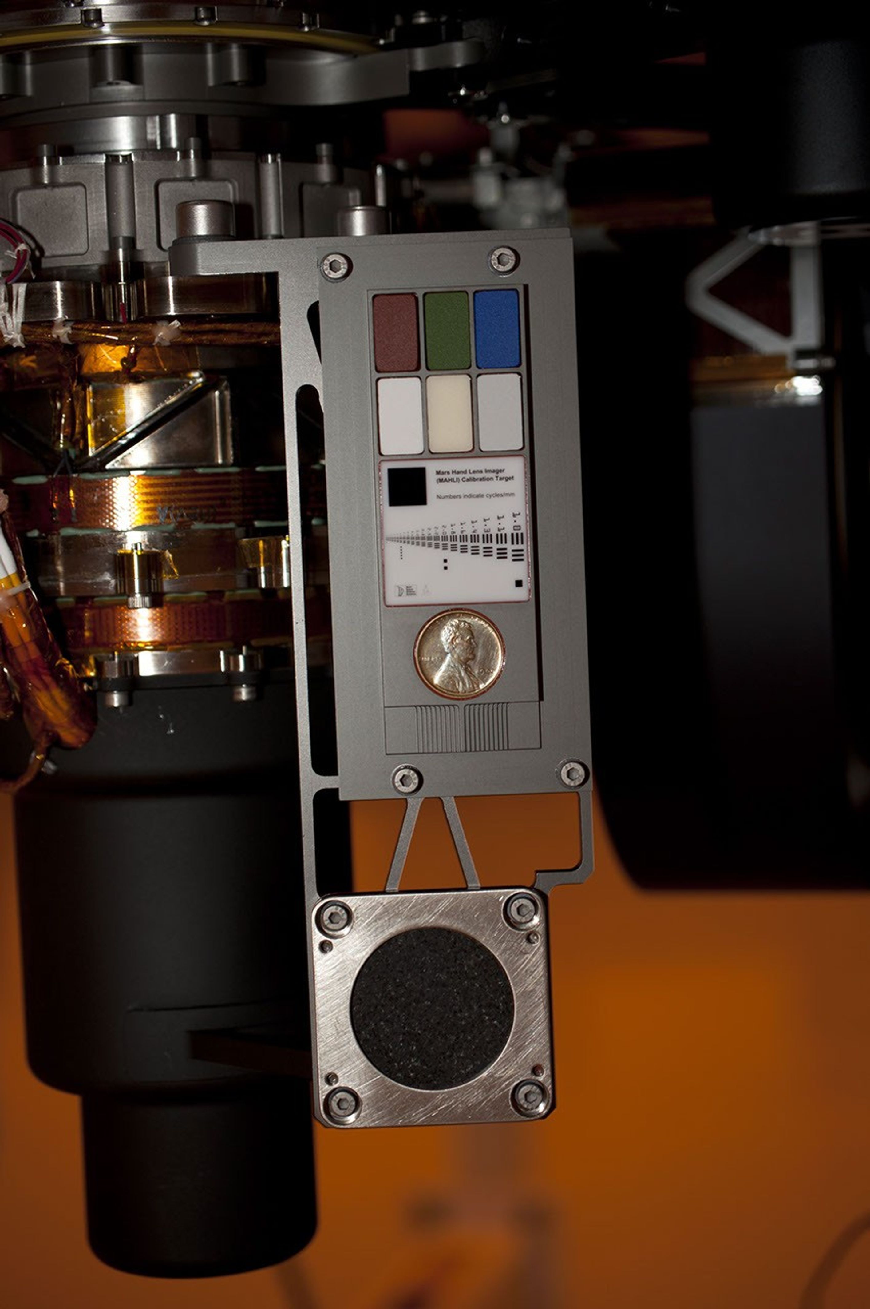 Two instruments at the end of the robotic arm on NASA's Mars rover Curiosity will use calibration targets attached to a shoulder joint of the arm. The penny is a size reference giving the public a familiar object for perceiving size on Mars easily.