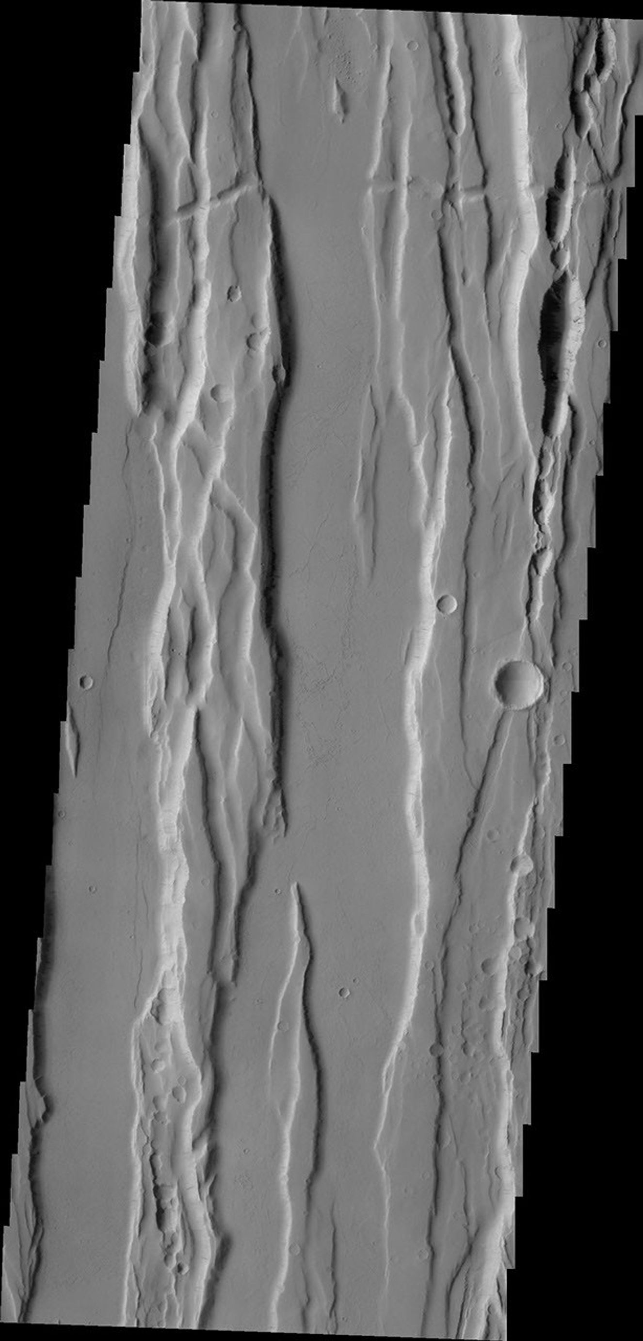 The north-south trending fractures and graben (block down-dropped between two fractures) in this region are called Ceraunius Fossae and are likely related to Alba Mons to the north shown in this image from NASA's 2001 Mars Odyssey spacecraft.