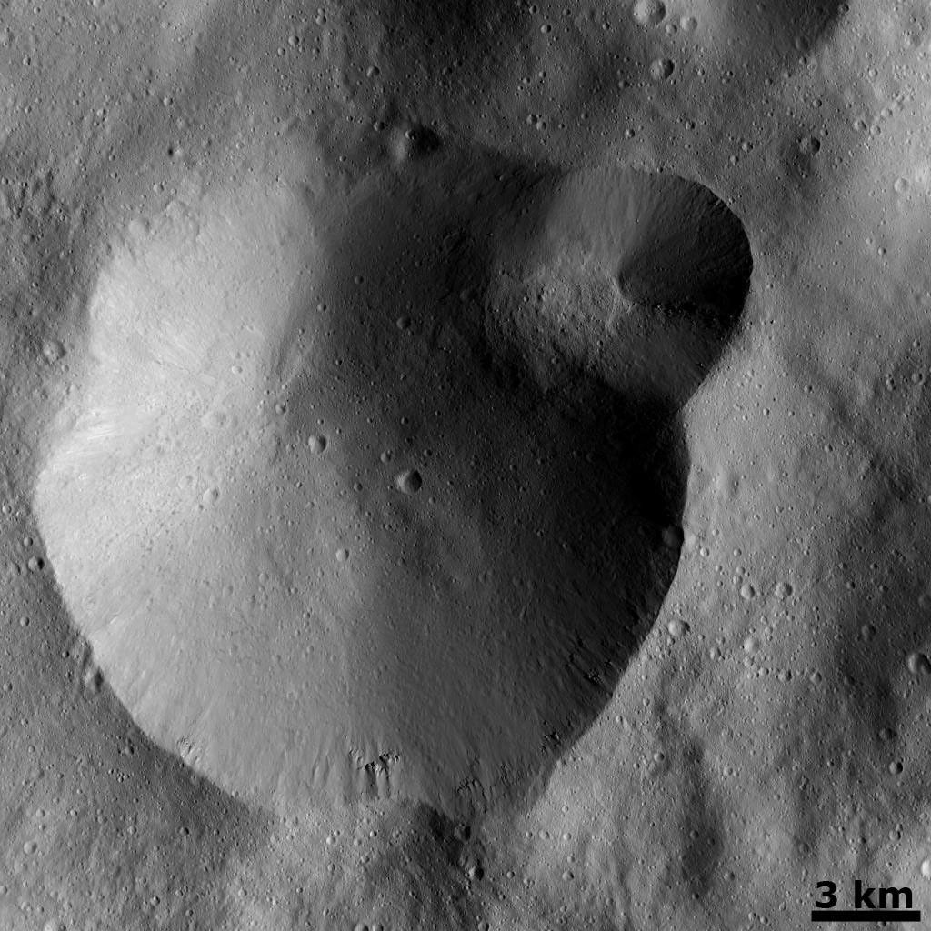 This image from NASA's Dawn spacecraft shows two overlapping impact craters on asteroid Vesta. The rims of the craters are both reasonably fresh but the larger crater must be older because the smaller crater cuts across the larger crater's rim.