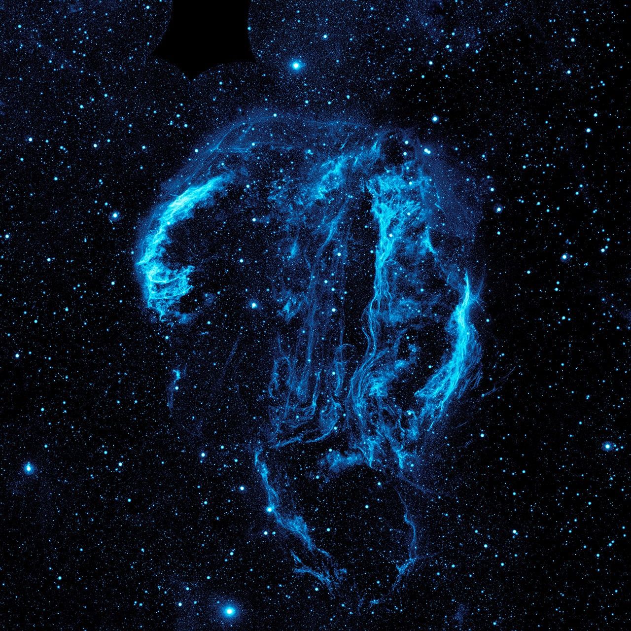 Wispy tendrils of hot dust and gas glow brightly in this ultraviolet image of the Cygnus Loop nebula, taken by NASA's Galaxy Evolution Explorer. The nebula lies about 1,500 light-years away.