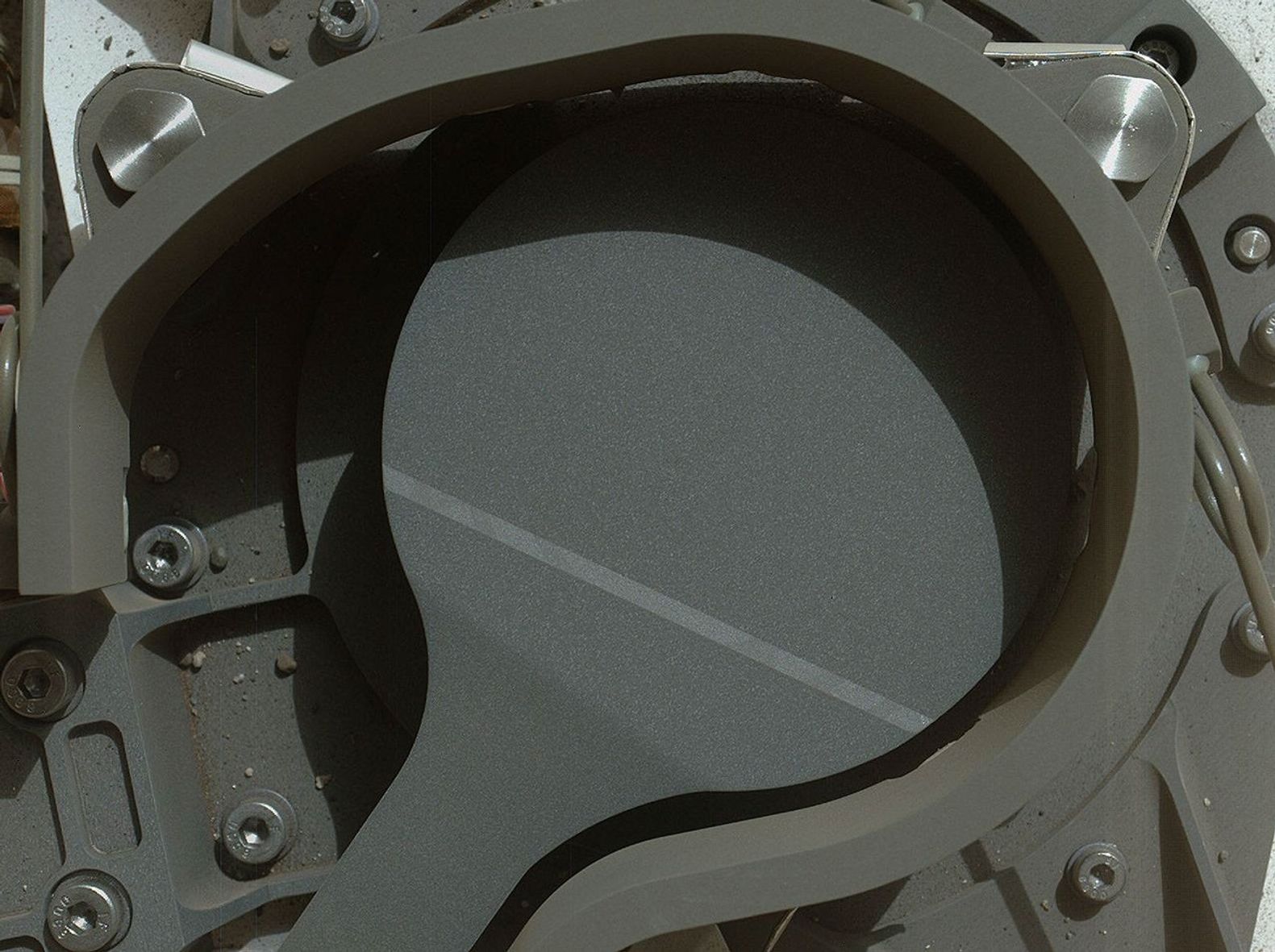 This image from NASA's Curiosity rover shows the cover on an inlet that will receive powdered rock and soil samples for analysis. The image also shows sand and angular and rounded pebbles that were deposited on the rover deck when it landed.