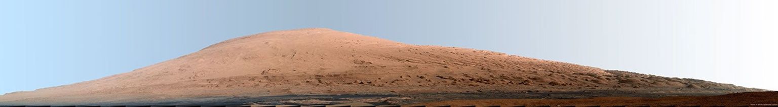 This mosaic of images from the Mast Camera (Mastcam) on NASA's Mars rover Curiosity shows Mount Sharp in a white-balanced color adjustment that makes the sky look overly blue but shows the terrain as if under Earth-like lighting.