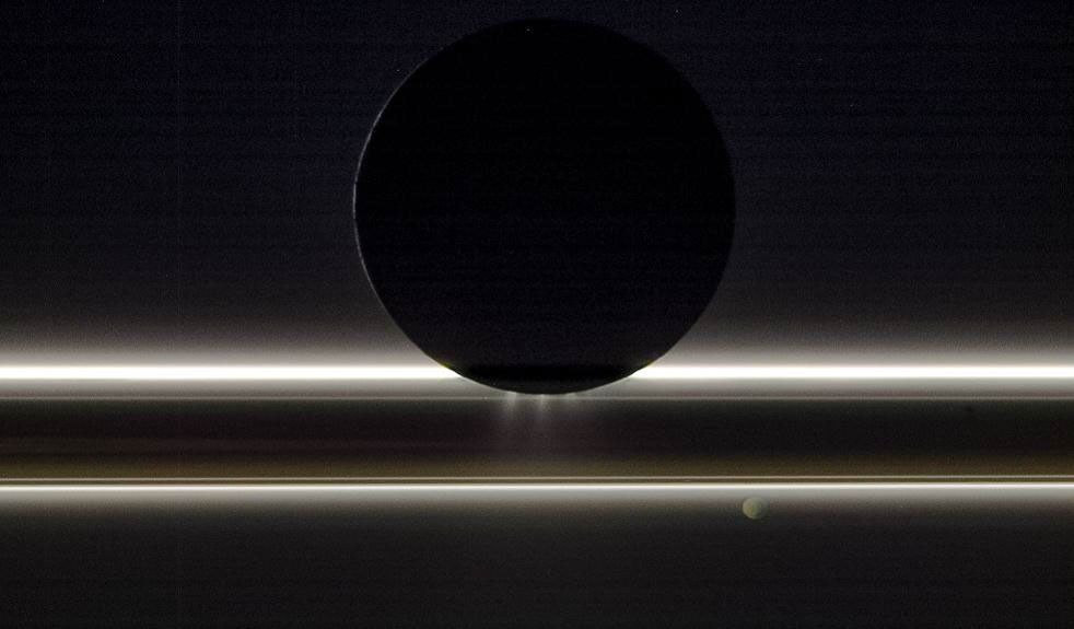 Saturn's moon Enceladus drifts before the rings and the tiny moon Pandora in this view captured by NASA's Cassini spacecraft on Nov. 1, 2009. The Sun provides striking illumination for the icy particles that make up both the rings and the jets.