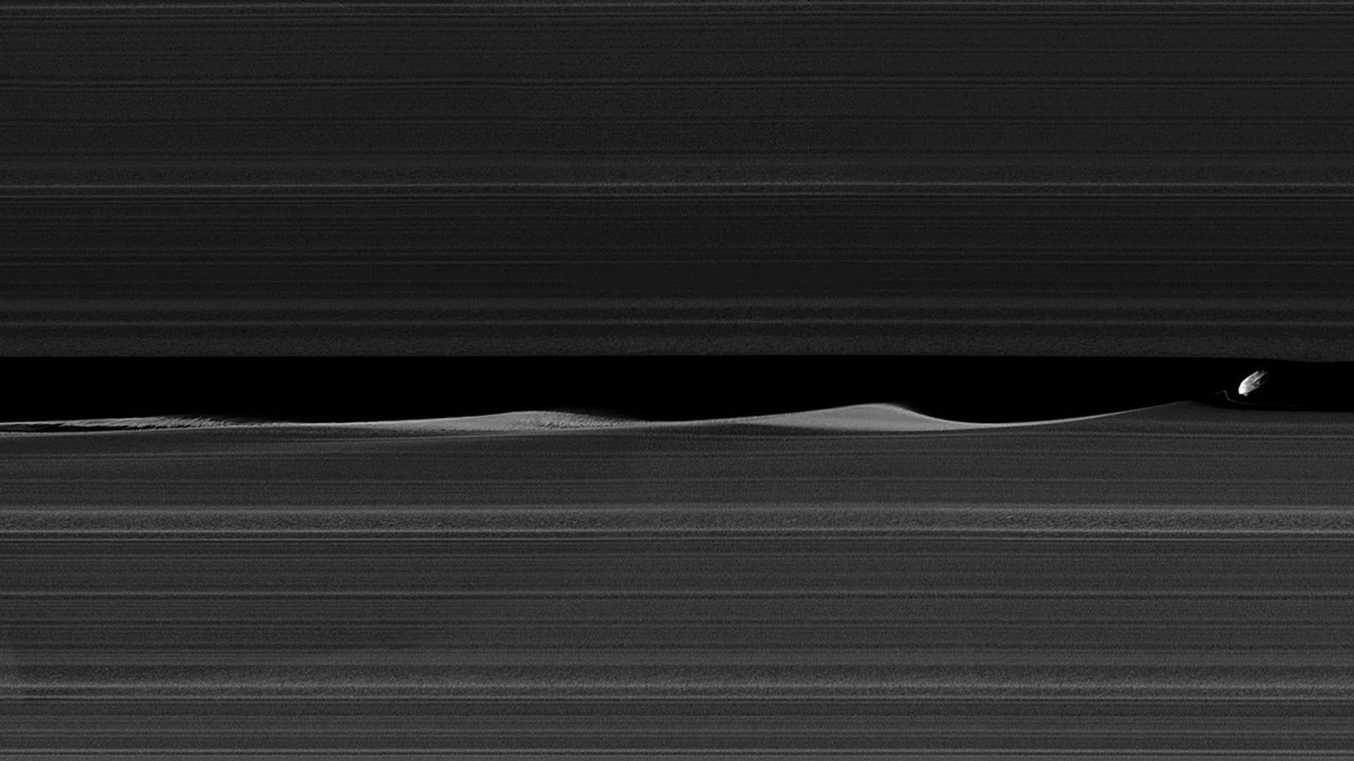 Daphnis, one of Saturn's ring-embedded moons, is featured in this view from NASA's Cassini spacecraft, kicking up waves as it orbits within the Keeler gap.