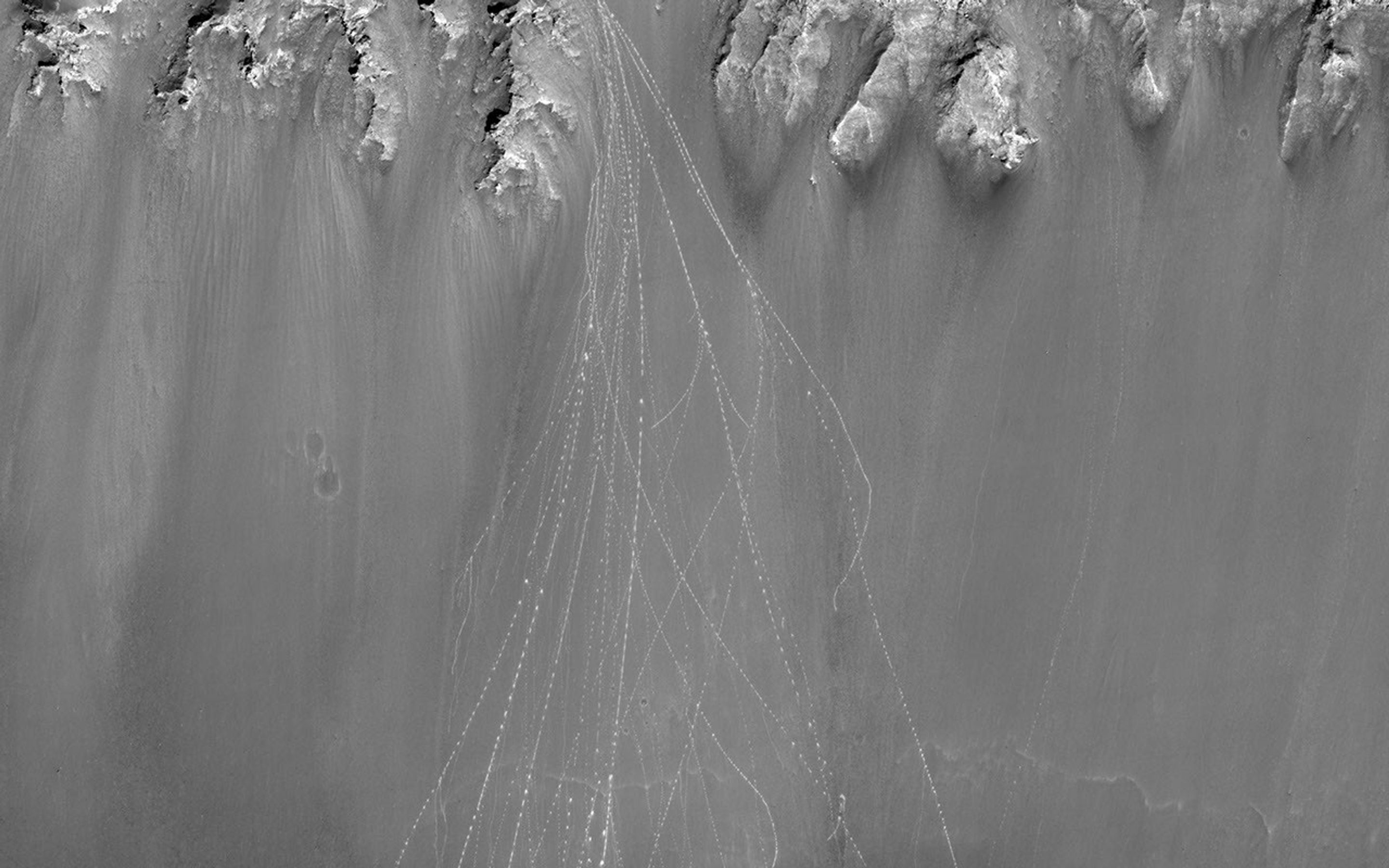 When boulders roll down a dusty Martian slope, they can leave long, dotted tracks behind on the slope surface as seen in this observation from NASA's Mars Reconnaissance Orbiter.