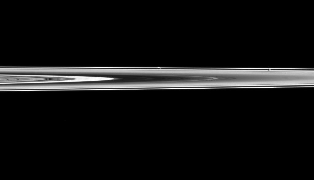 Prometheus and Pandora are almost hidden in Saturn's rings in this image captured by NASA's Cassini spacecraft. Prometheus is the left most moon in the ring plane, roughly in the center of the image. Pandora is towards the right.