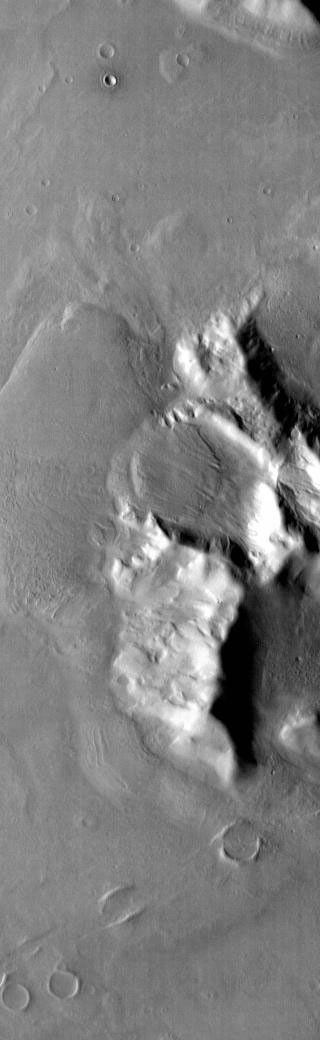 This infrared image captured by NASA's 2001 Mars Odyssey spacecraft shows bright toned material, which is warmer than dark toned surfaces. Material has moved downslope from the top of this hill in Promethei Terra.