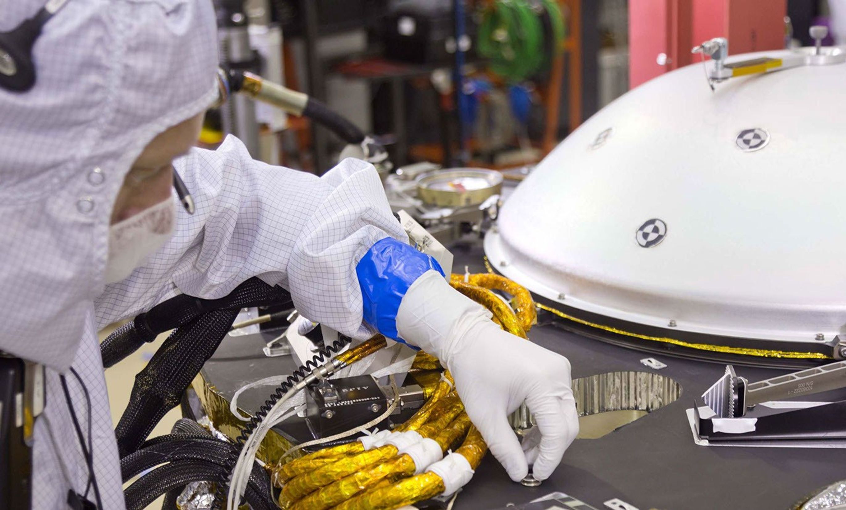A spacecraft specialist in a clean room at Lockheed Martin Space Systems in Denver affixes a dime-size chip onto the lander deck in November 2015. This chip carries 826,923 names, submitted by the public online from all over the world.