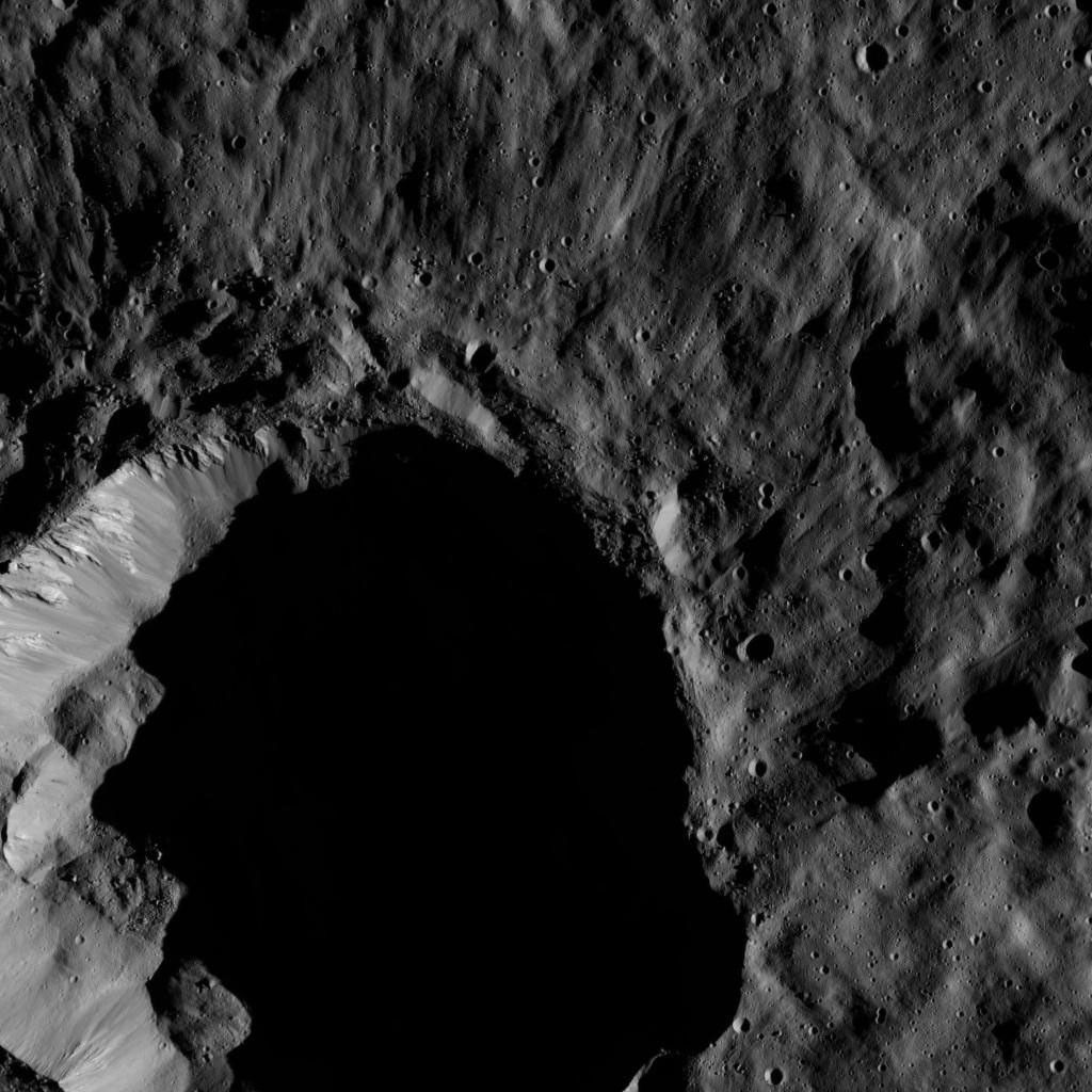 This view from NASA's Dawn spacecraft shows a moderate-sized impact feature that is imprinted upon the southern rim of Mondamin Crater. Boulders of various sizes can be seen around the crater's rim and on the sunlit part of its floor.