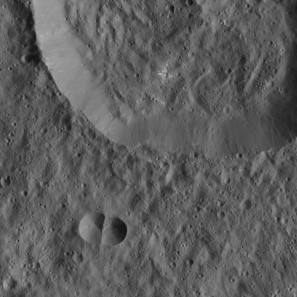 This image from NASA's Dawn spacecraft of Ceres shows a small, double-impact crater (at bottom) near a larger crater. The larger structure has a crater floor with roughly the same crater density.