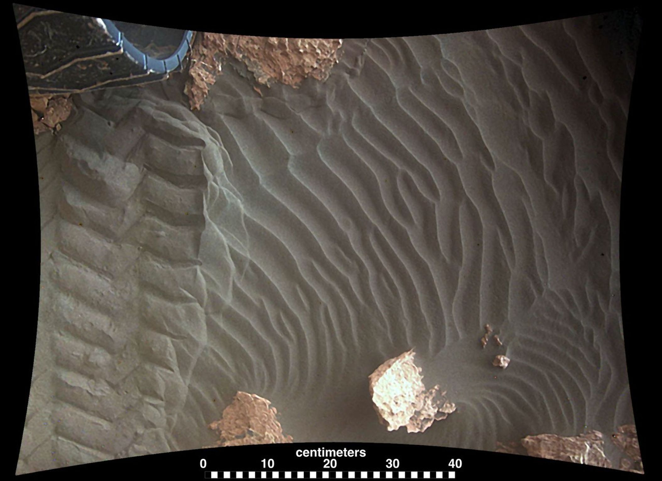 This image from an animation shows wind blowing sand underneath NASA's Curiosity Mars rover on a non-driving day for the rover.