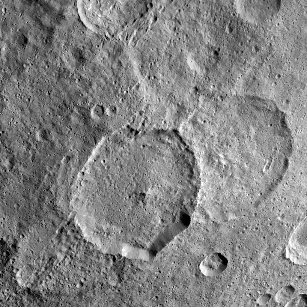 Inamahari Crater on Ceres, the large well-defined crater at the center of this image from NASA's Dawn spacecraft, is one of the sites where scientists have discovered evidence for organic material.