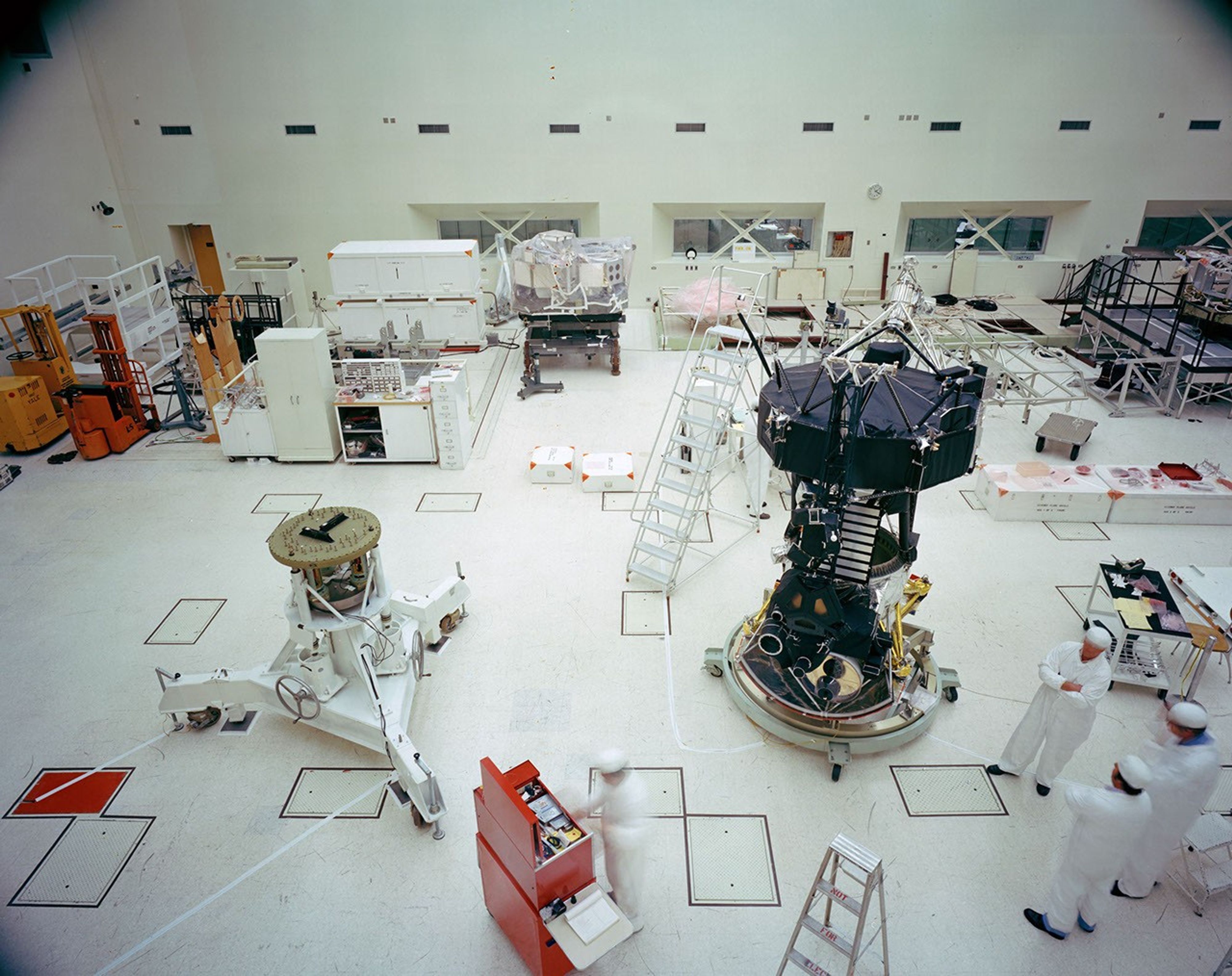 This archival photo shows the Voyager Proof Test Model (in the foreground right of center) undergoing a mechanical preparation and weight center of gravity test at NASA's Jet Propulsion Laboratory, Pasadena, California, on January 12, 1977.