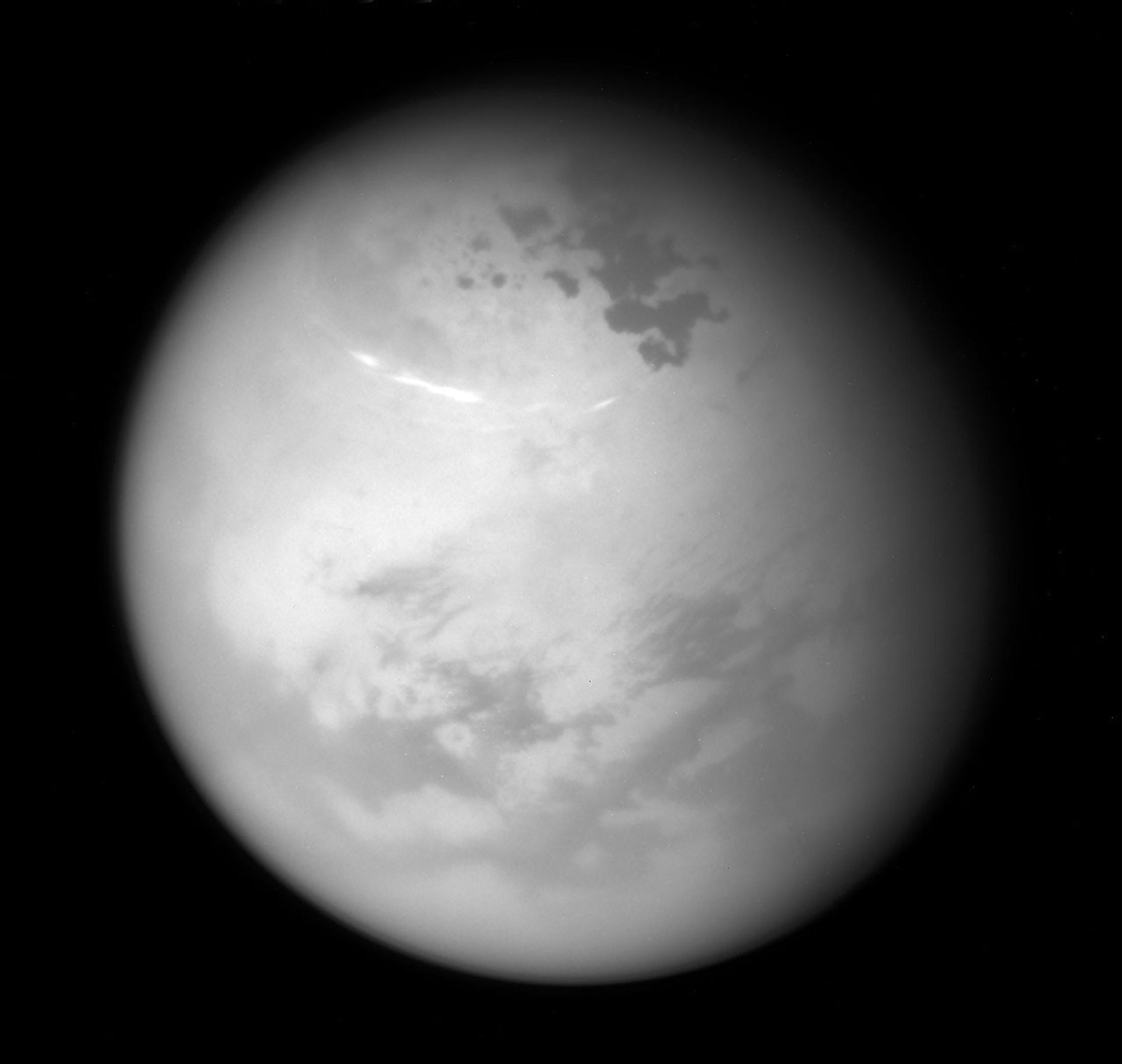 NASA's Cassini spacecraft sees bright methane clouds drifting in the summer skies of Saturn's moon Titan, along with dark hydrocarbon lakes and seas clustered around the north pole.
