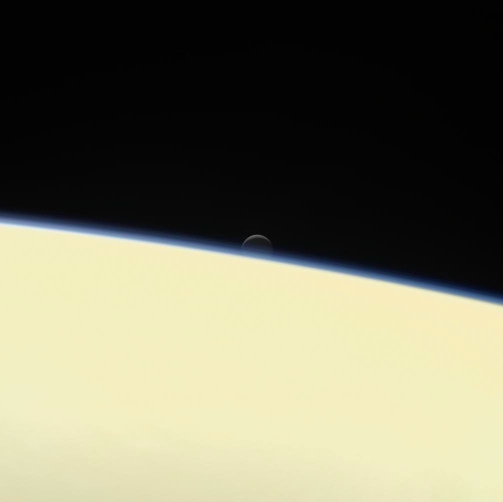 Saturn's active, ocean-bearing moon Enceladus sinks behind the giant planet in a farewell portrait from NASA's Cassini spacecraft. This view of Enceladus was taken by the Cassini spacecraft on Sept. 13, 2017.