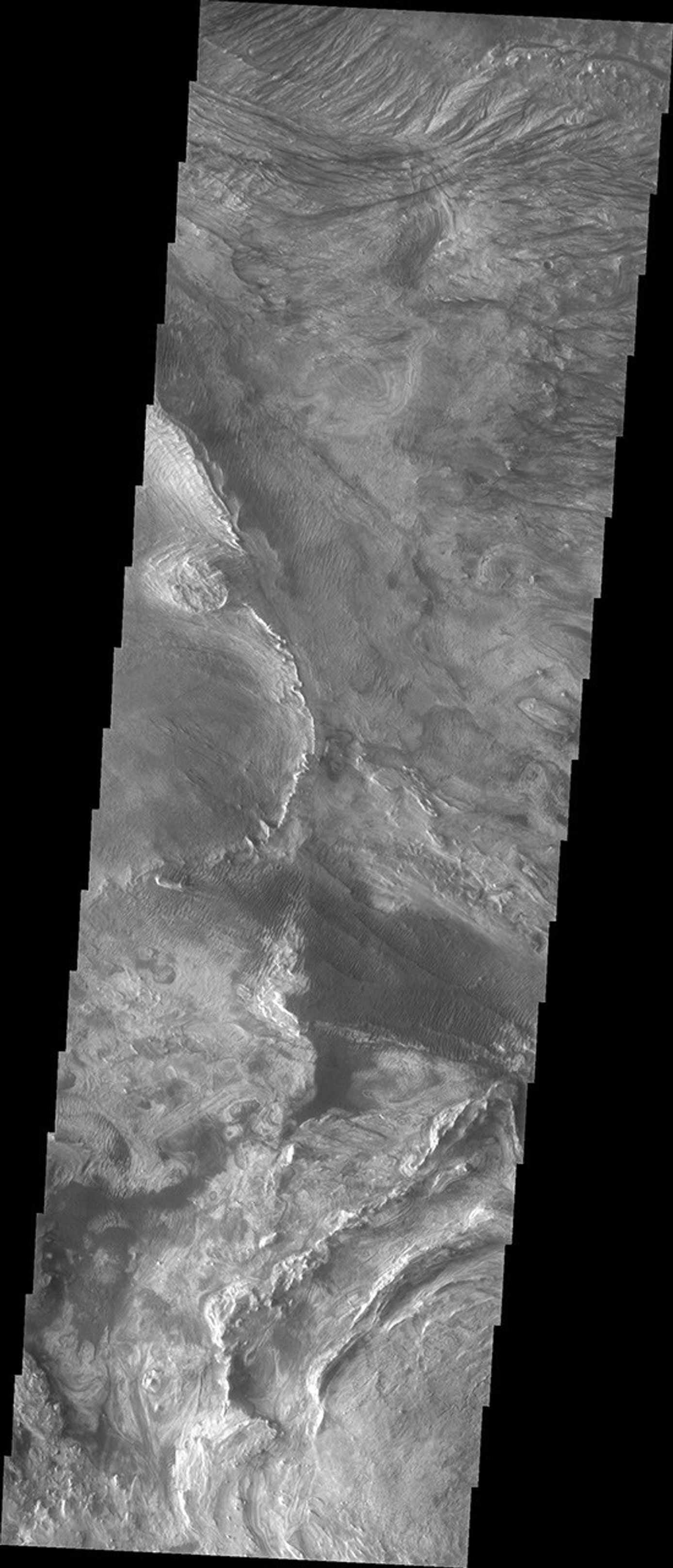 This image captured by NASA's 2001 Mars Odyssey spacecraft shows part of western Candor and the erosion of a large mesa. Layered materials are visible throughout the image.