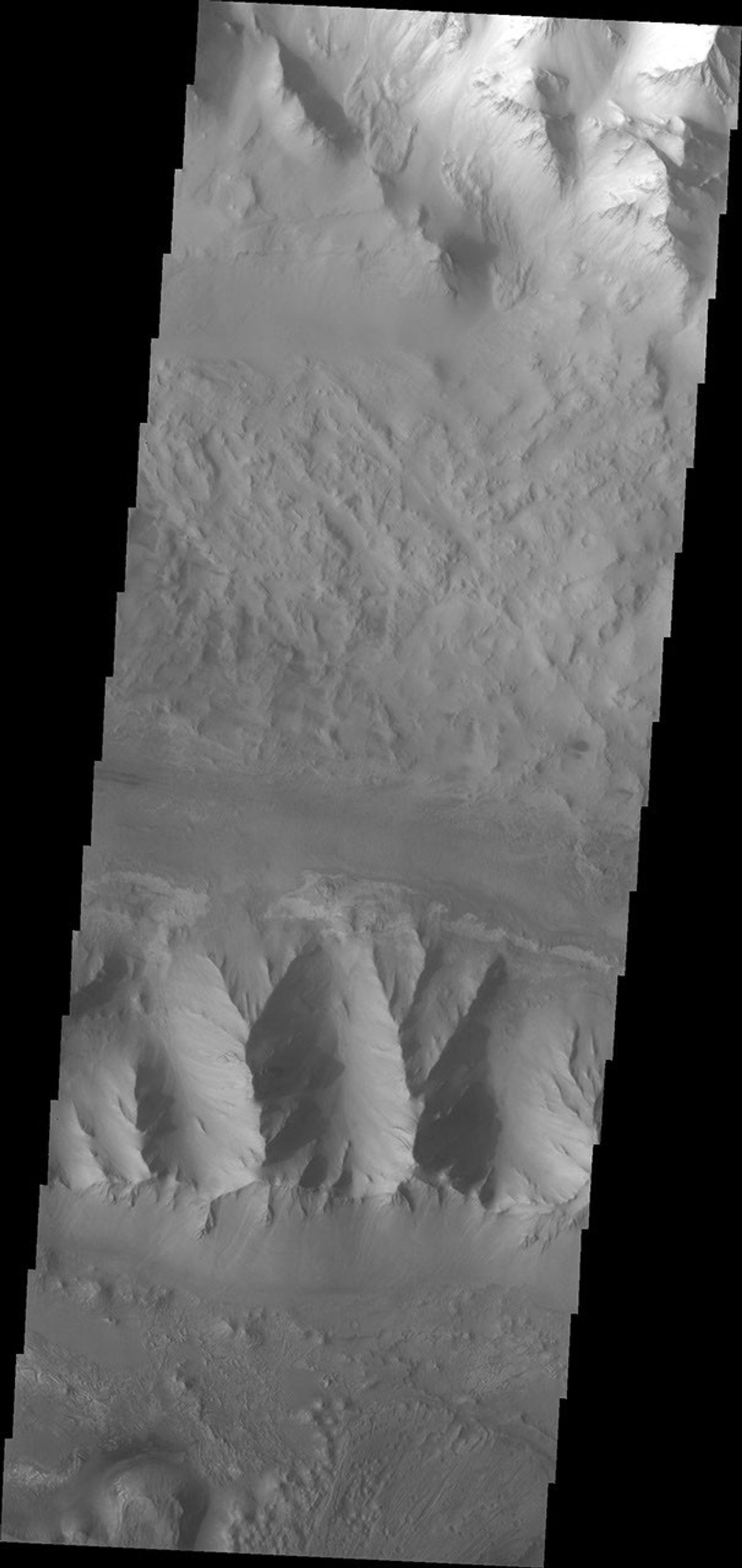 This image from NASA's 2001 Mars Odyssey spacecraft shows the central part of Ius Chasma, where the canyon profile changes. What started as a large graben south of the main chasma wall has widened to create a central high ridge separating the chasm.
